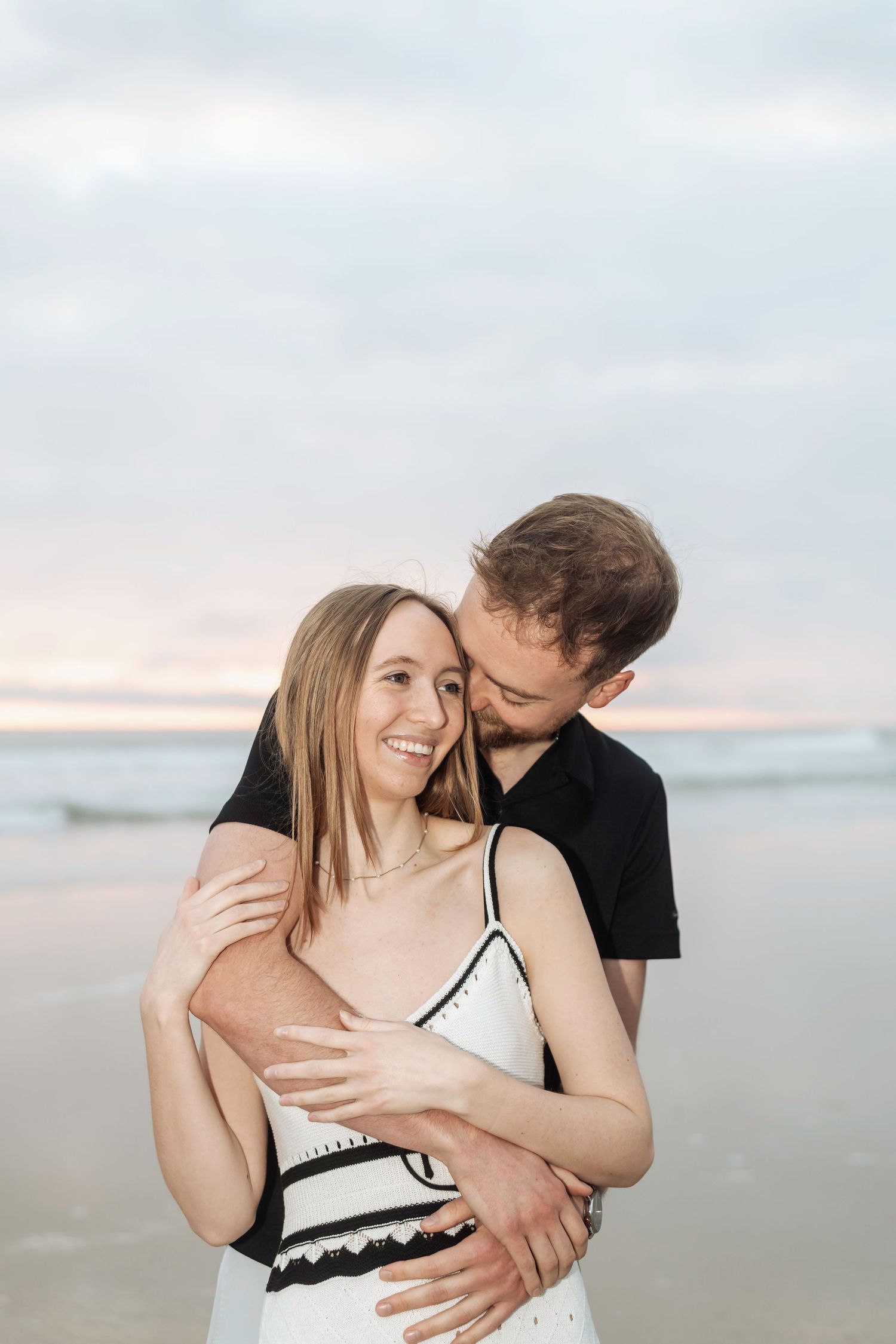 A tender beach portrait at sunset with soft natural lighting.