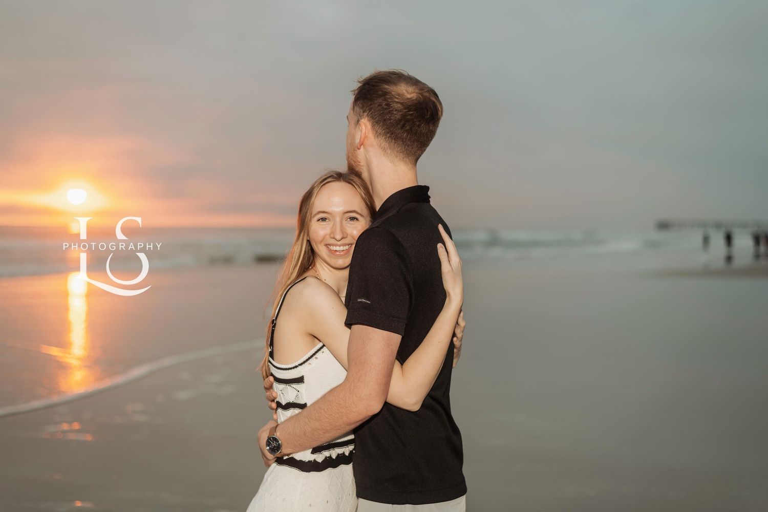 A romantic couple embracing on the beach during sunset.