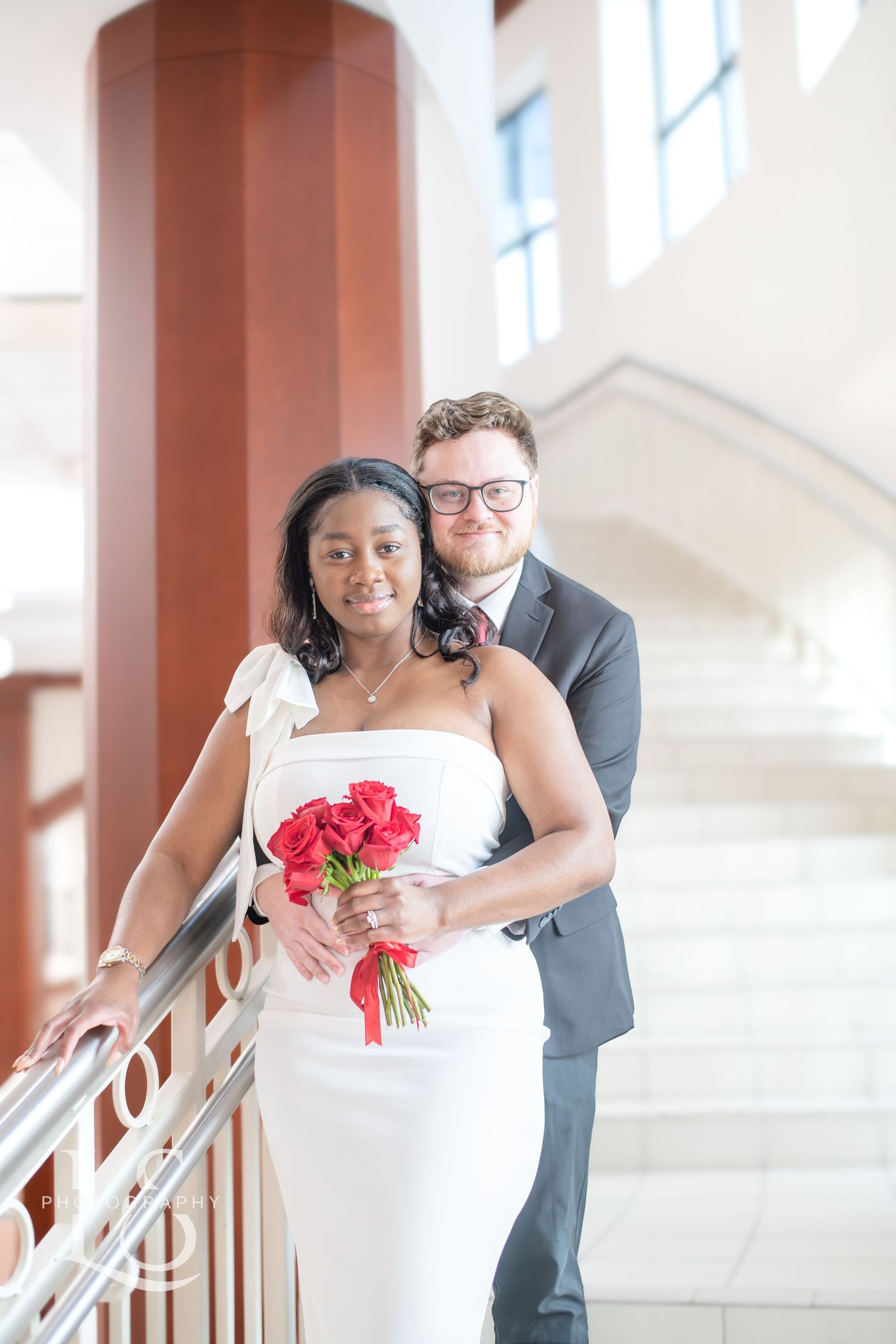 A romantic wedding photo session captured along a bright interior staircase with columns.