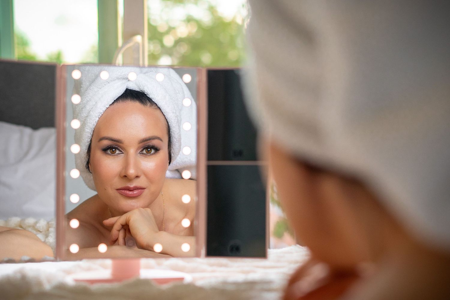 woman with towel lookin to the mirror