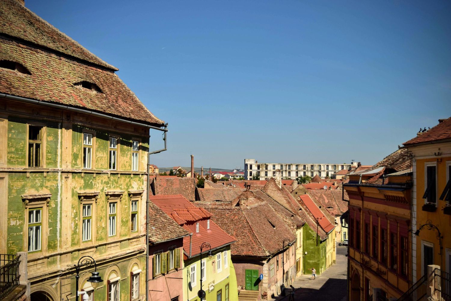 Wide-angle shot of a quaint Eastern European village, with old architecture and rustic charm framed by green hills.
