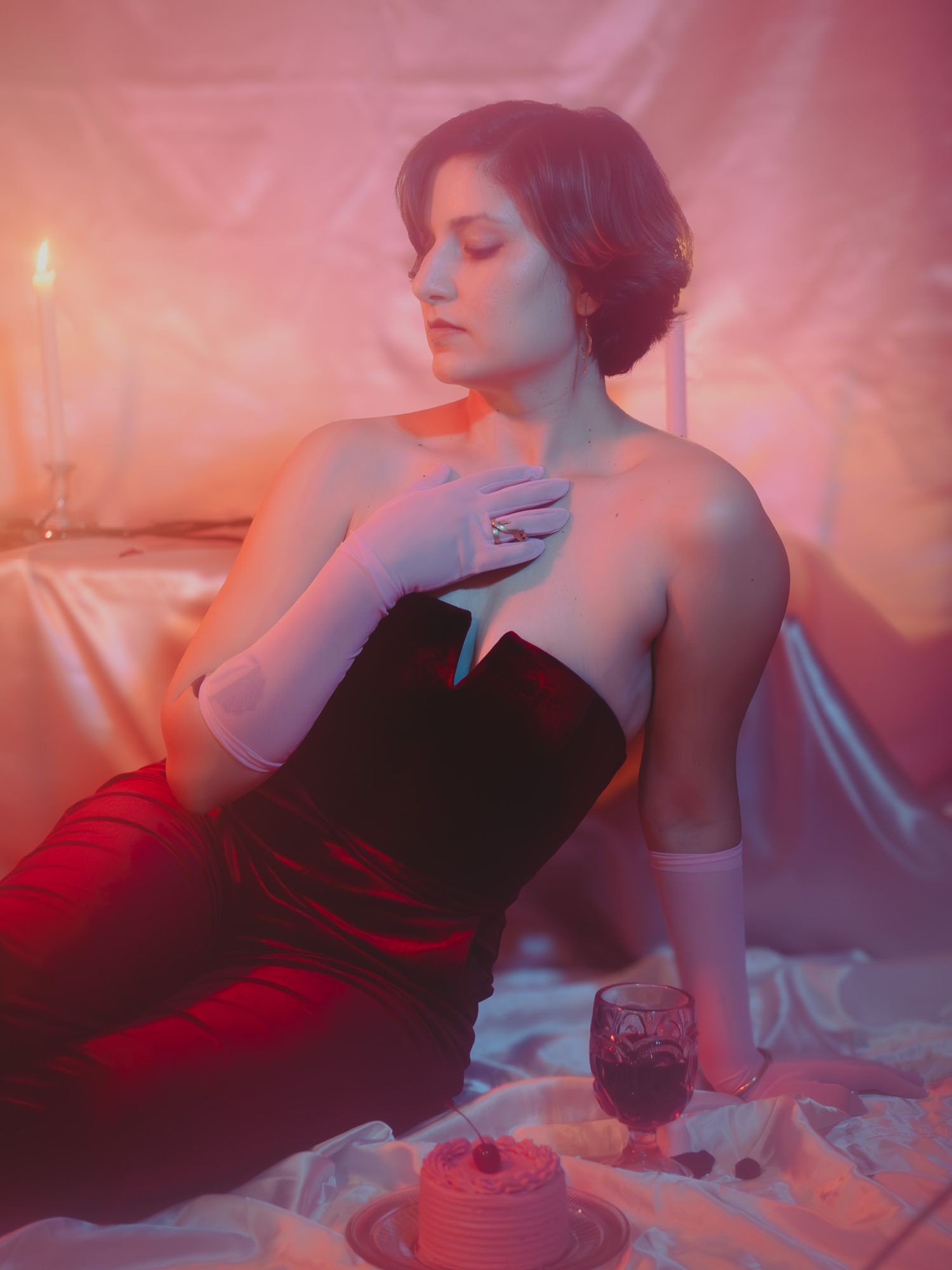 Model with bold makeup and dramatic attire, captured in a chic indoor studio with a minimalist backdrop.