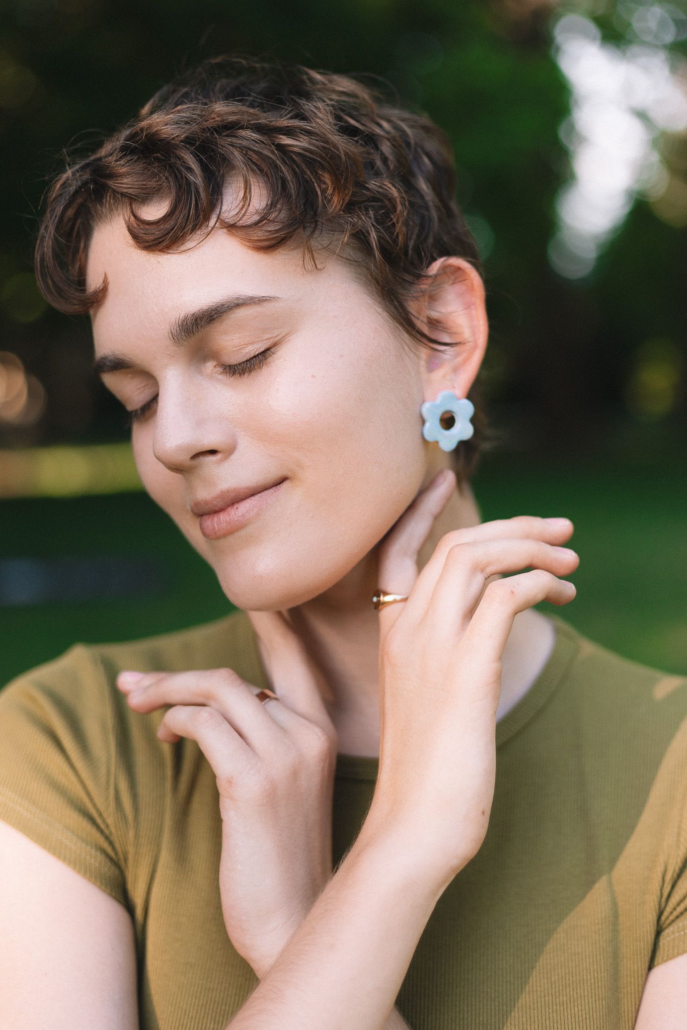 Model posing outdoors against a scenic backdrop of nature, with soft sunlight creating a warm glow