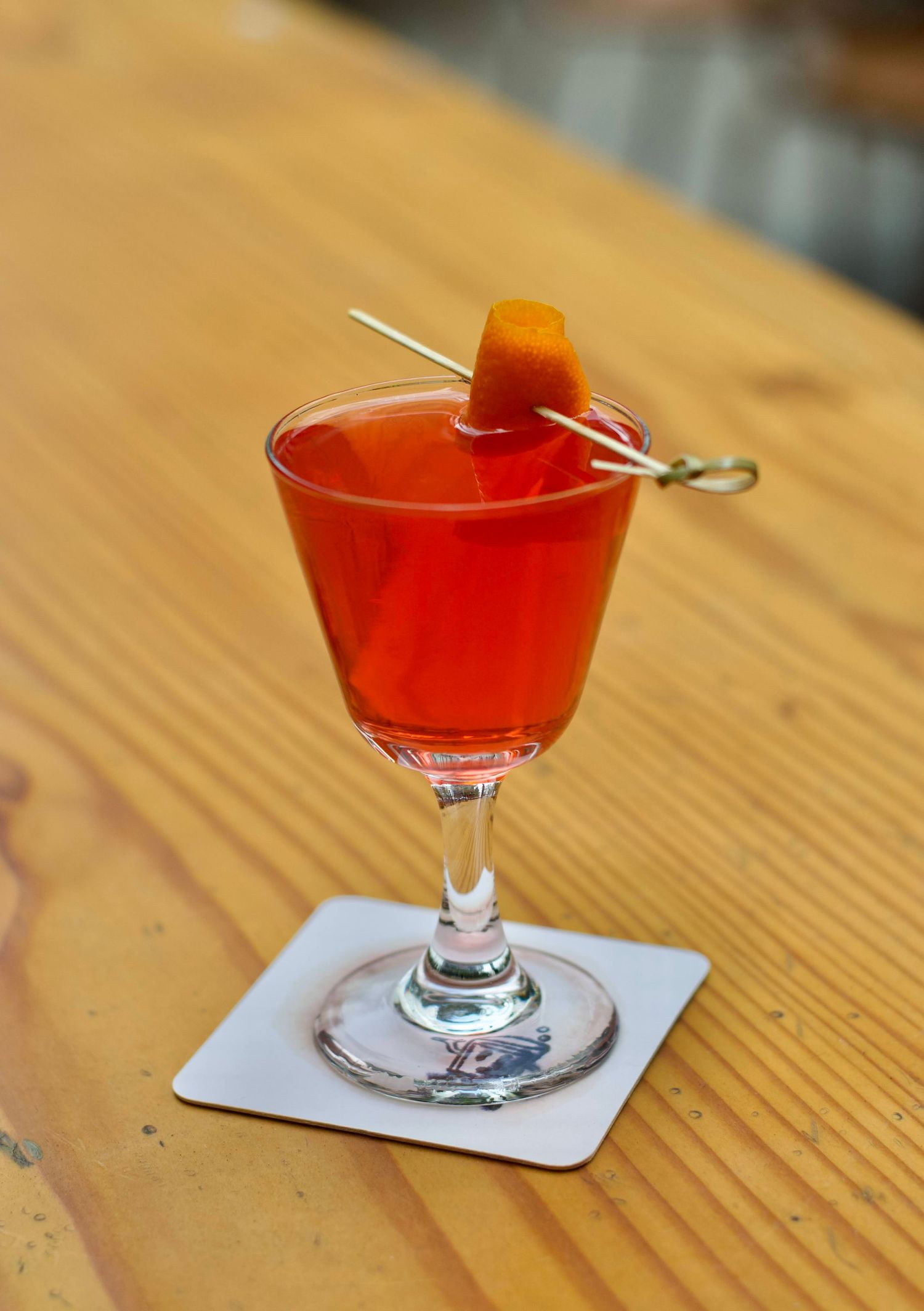 Close-up of a perfectly crafted cocktail with garnishes, set against a sleek bar backdrop with soft lighting highlighting the drink's vibran