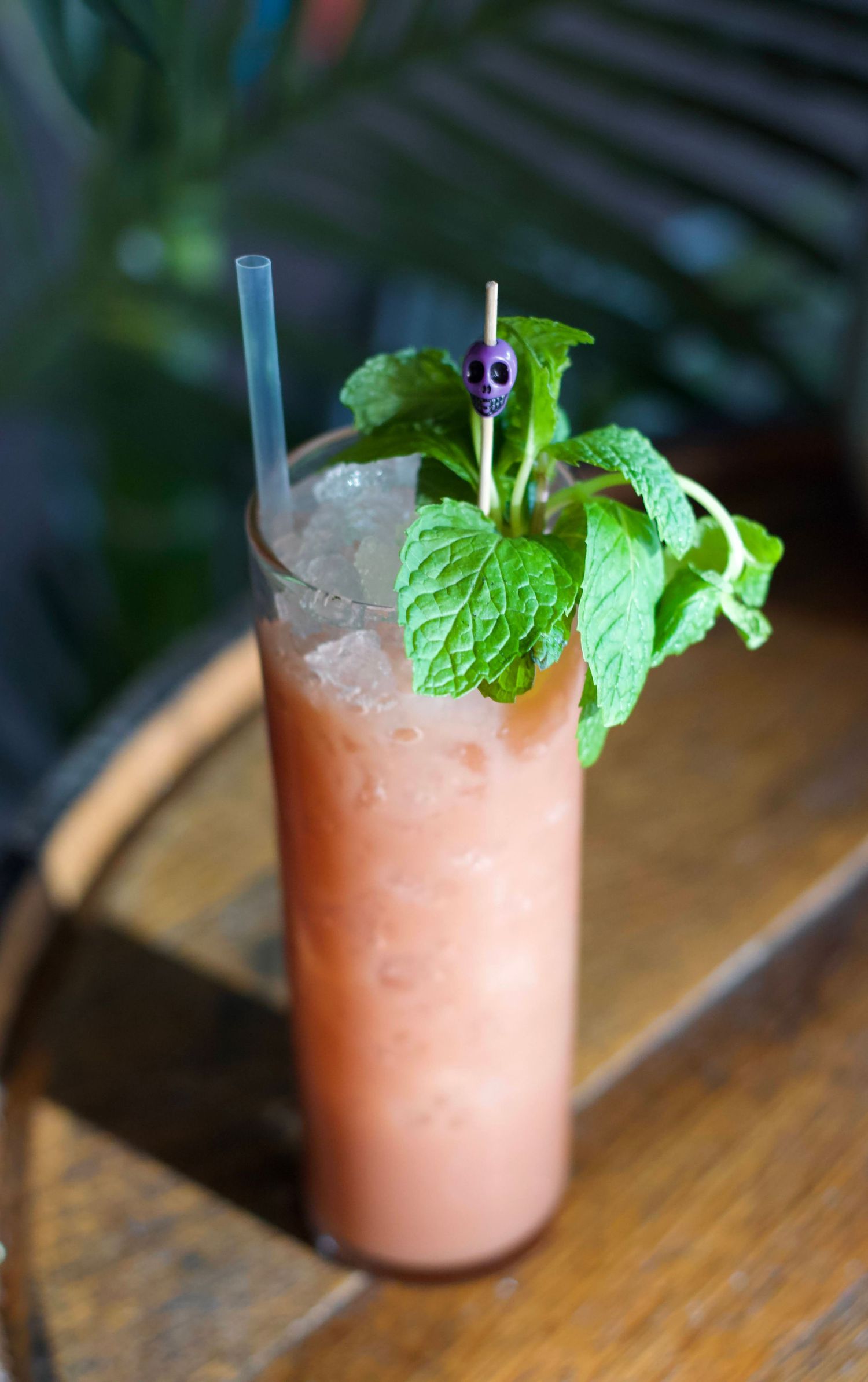 Elegant cocktail with a colorful gradient, topped with a fresh herb garnish, placed on a bar counter with soft lighting.