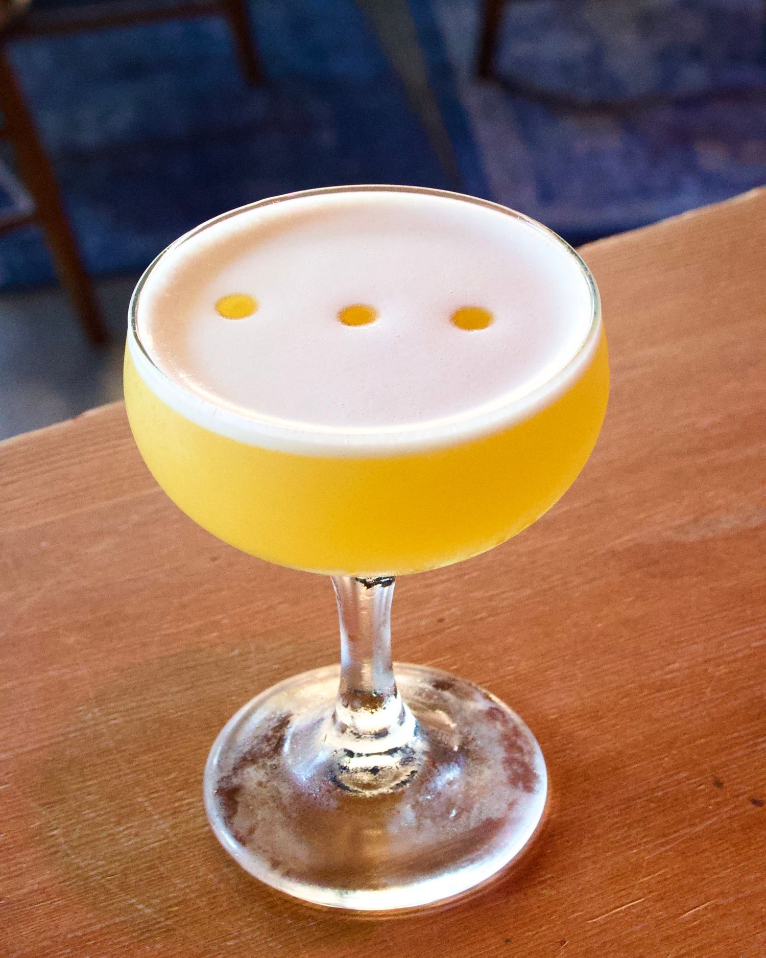 A refreshing cocktail with a splash of vibrant colors, resting on a wooden bar counter with soft lighting highlighting the drink's details.