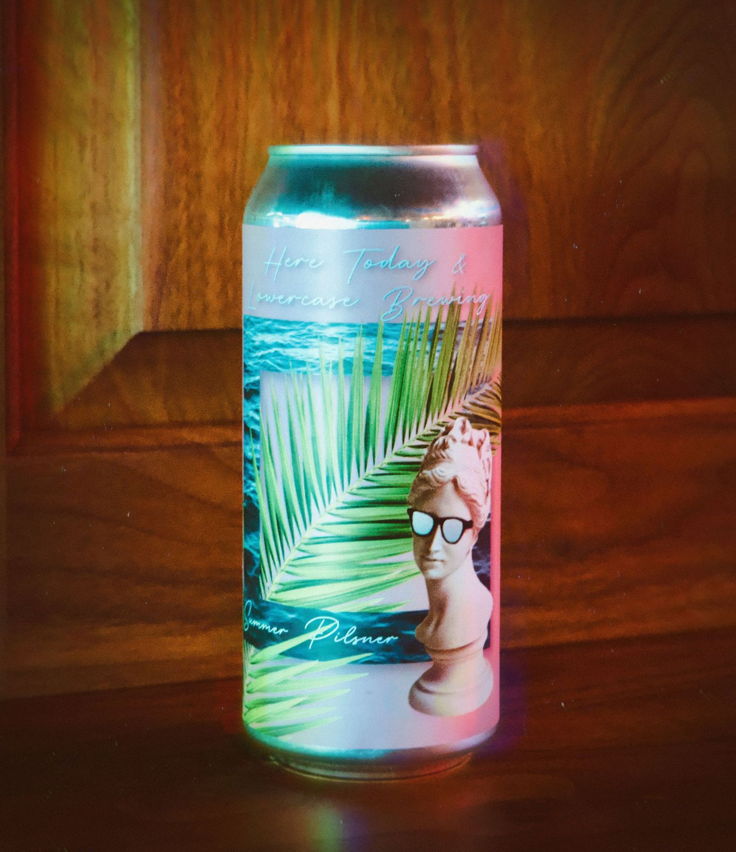 Close-up of a chilled beer can with condensation, resting on a wooden surface with a soft background blur.