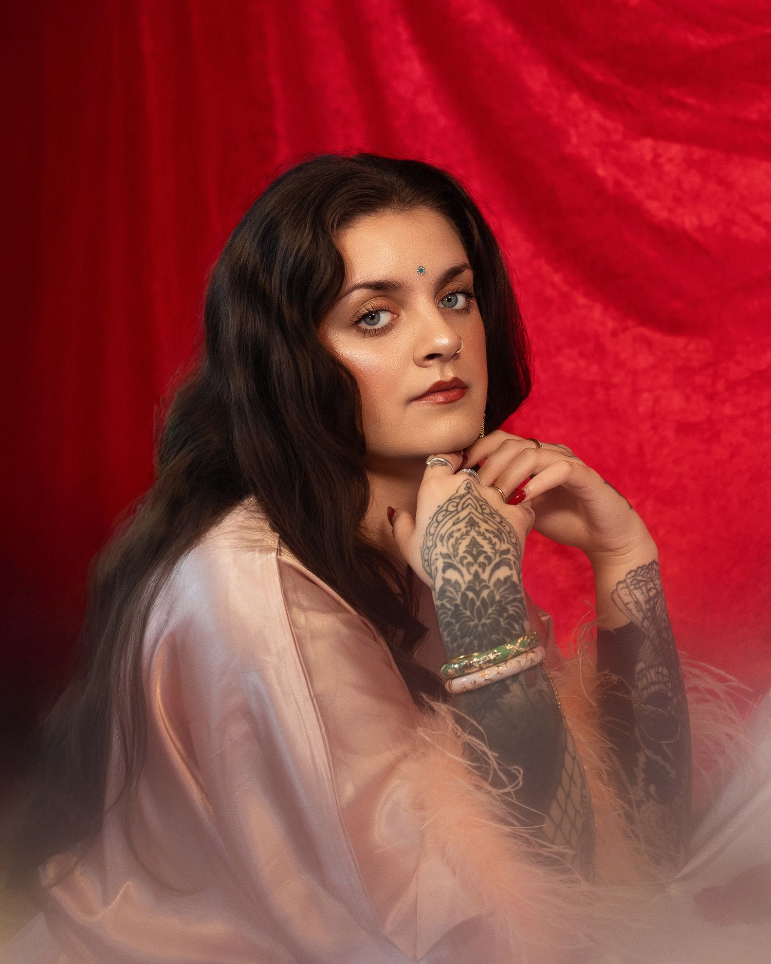 Closeup portrait of a model in a silk pink robe on a velvet red backdrop.