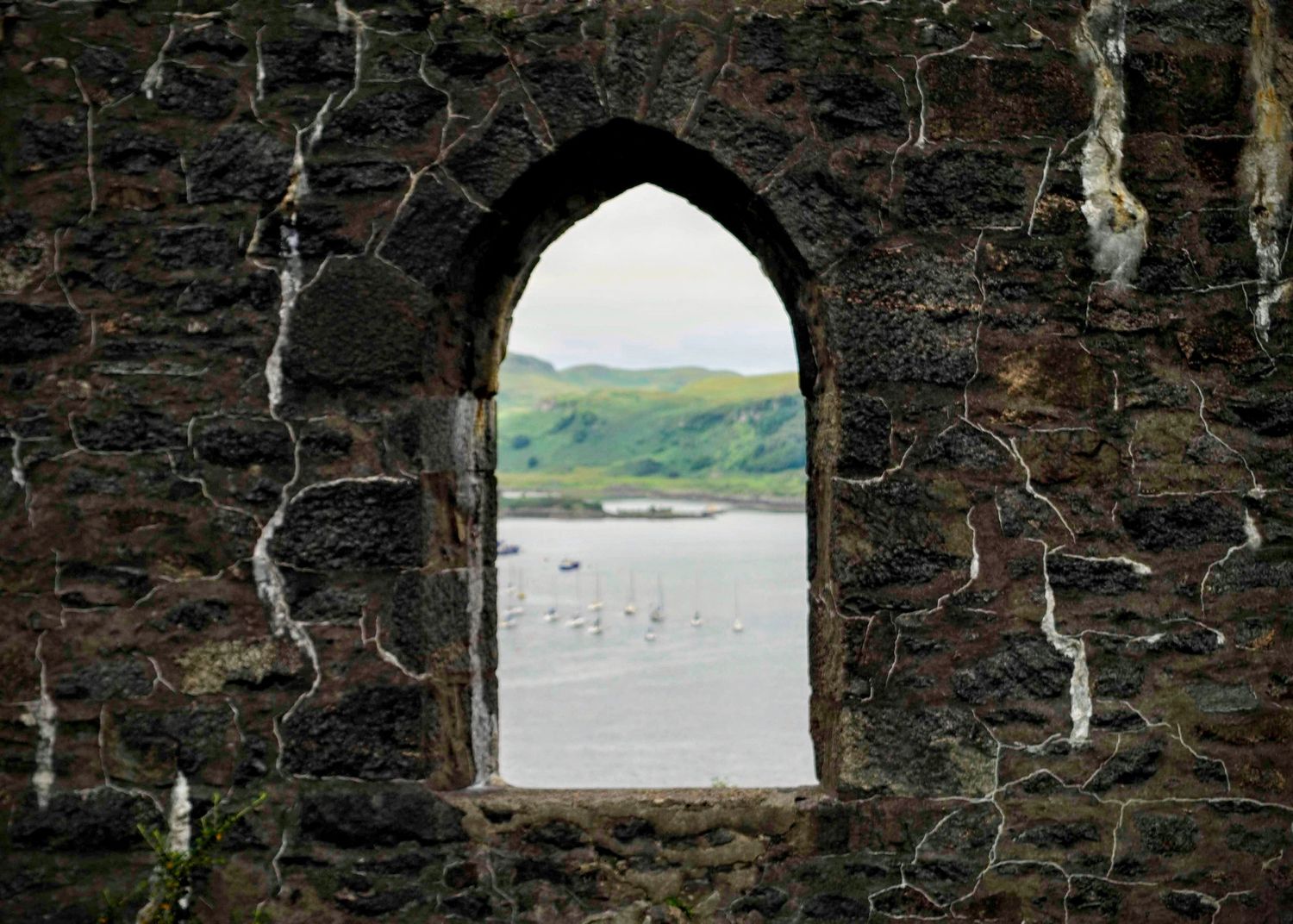 Ancient Scottish ruins, with crumbling stone walls set against a dramatic backdrop of misty mountains.