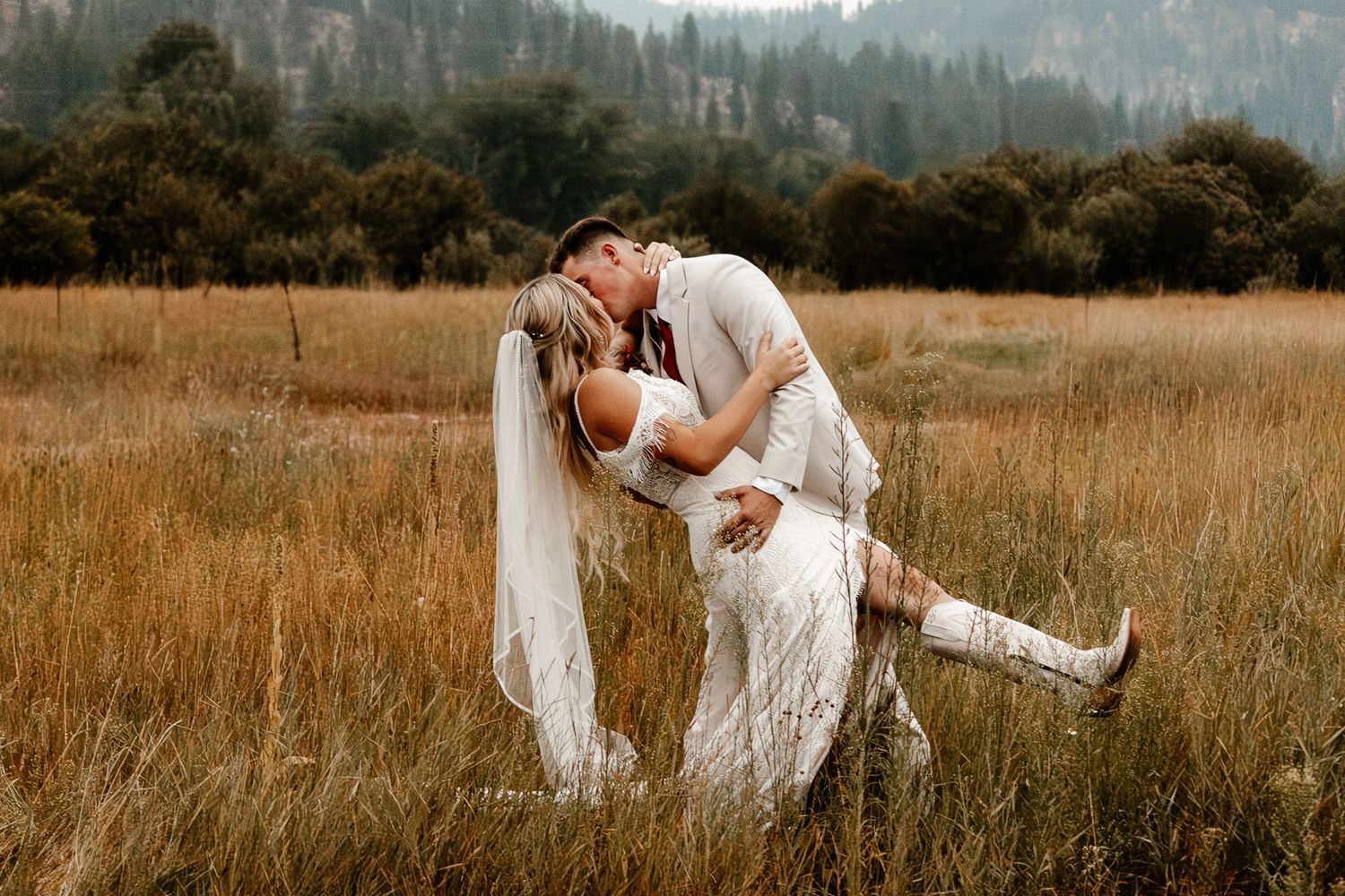 Couple cuddling in a field of tall grass, surrounded by nature's beauty and bathed in soft, natural light.