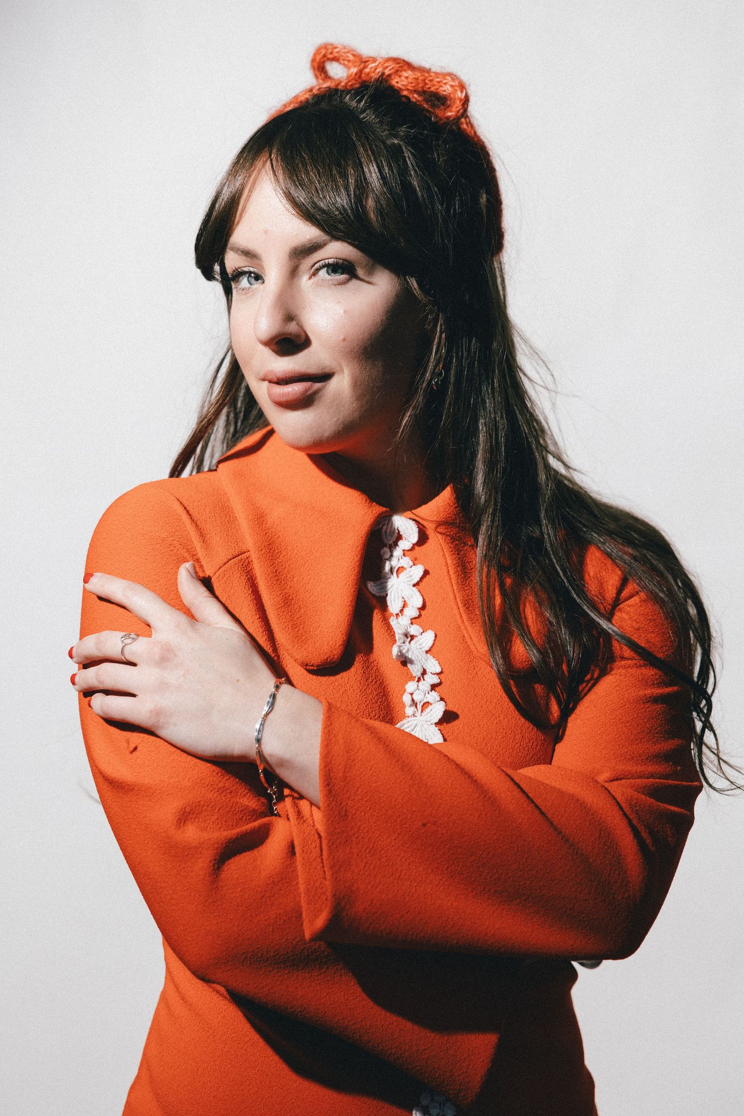 Four-panel fashion portrait of someone in a bright orange sweater with small white ghost pins against a light background.