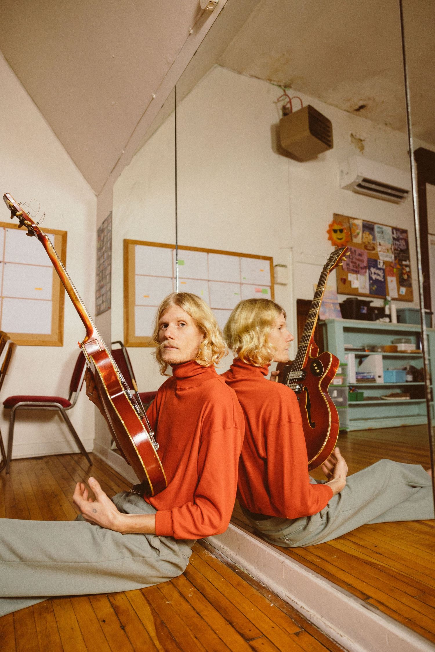Person in red sweater lying on wooden floor holding guitar seen from multiple angles in sequential artistic photos. Owen Steel