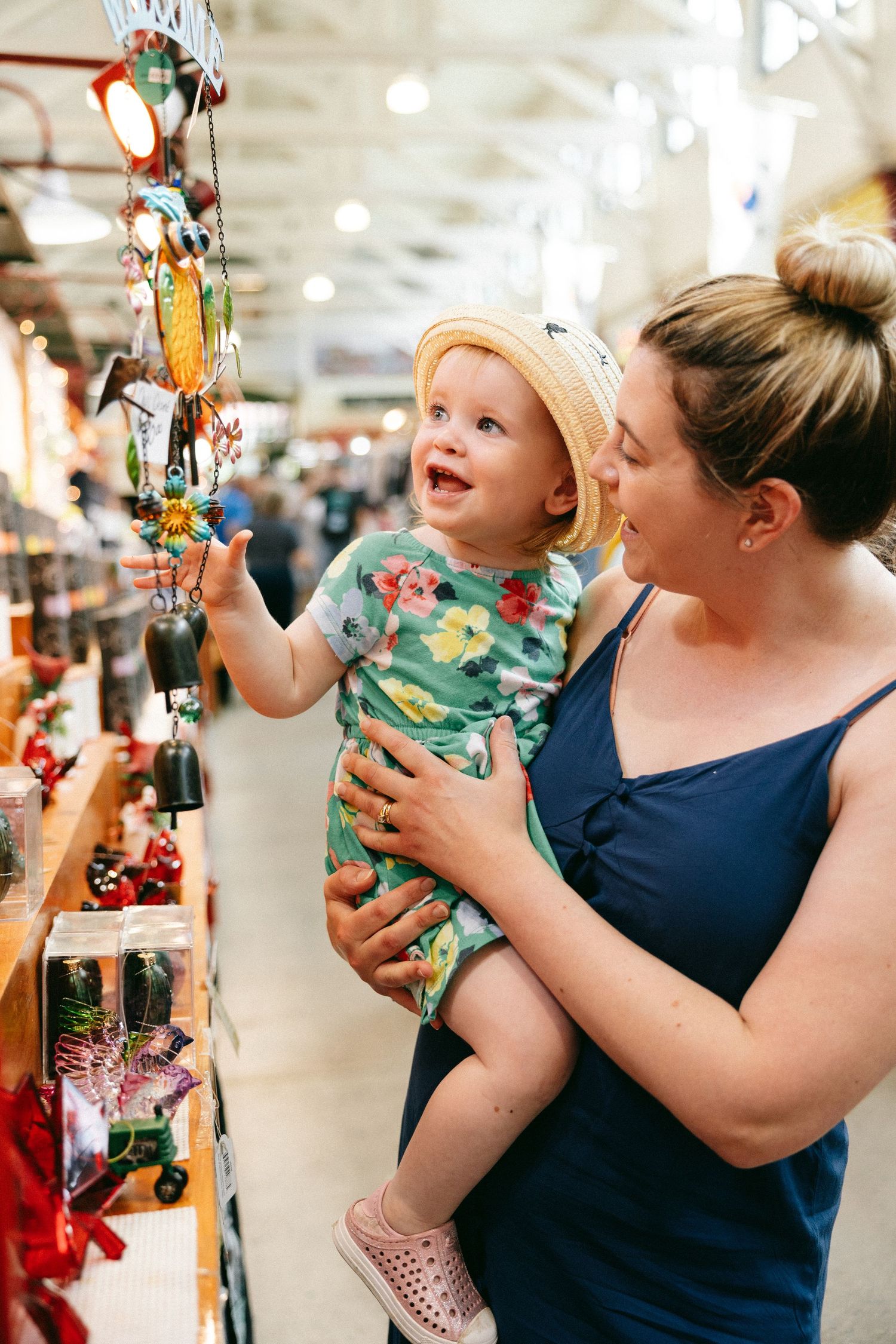 Parent and child look at hanging decorations together in a brightly lit retail store.
