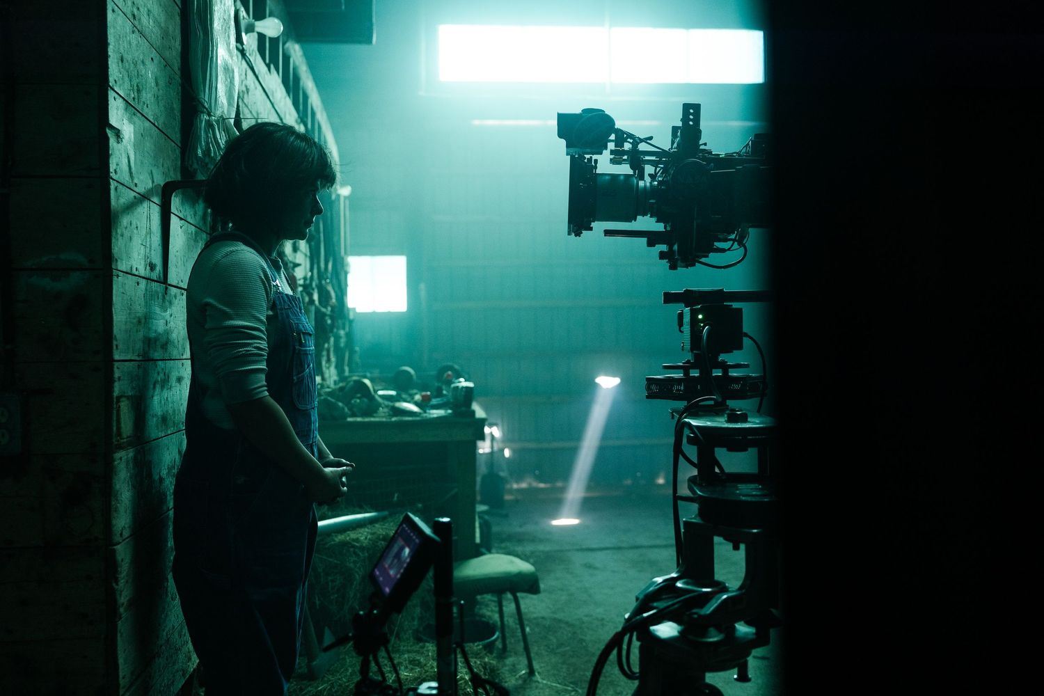 Behind-the-scenes film production shot in dark room with teal lighting and professional camera equipment.