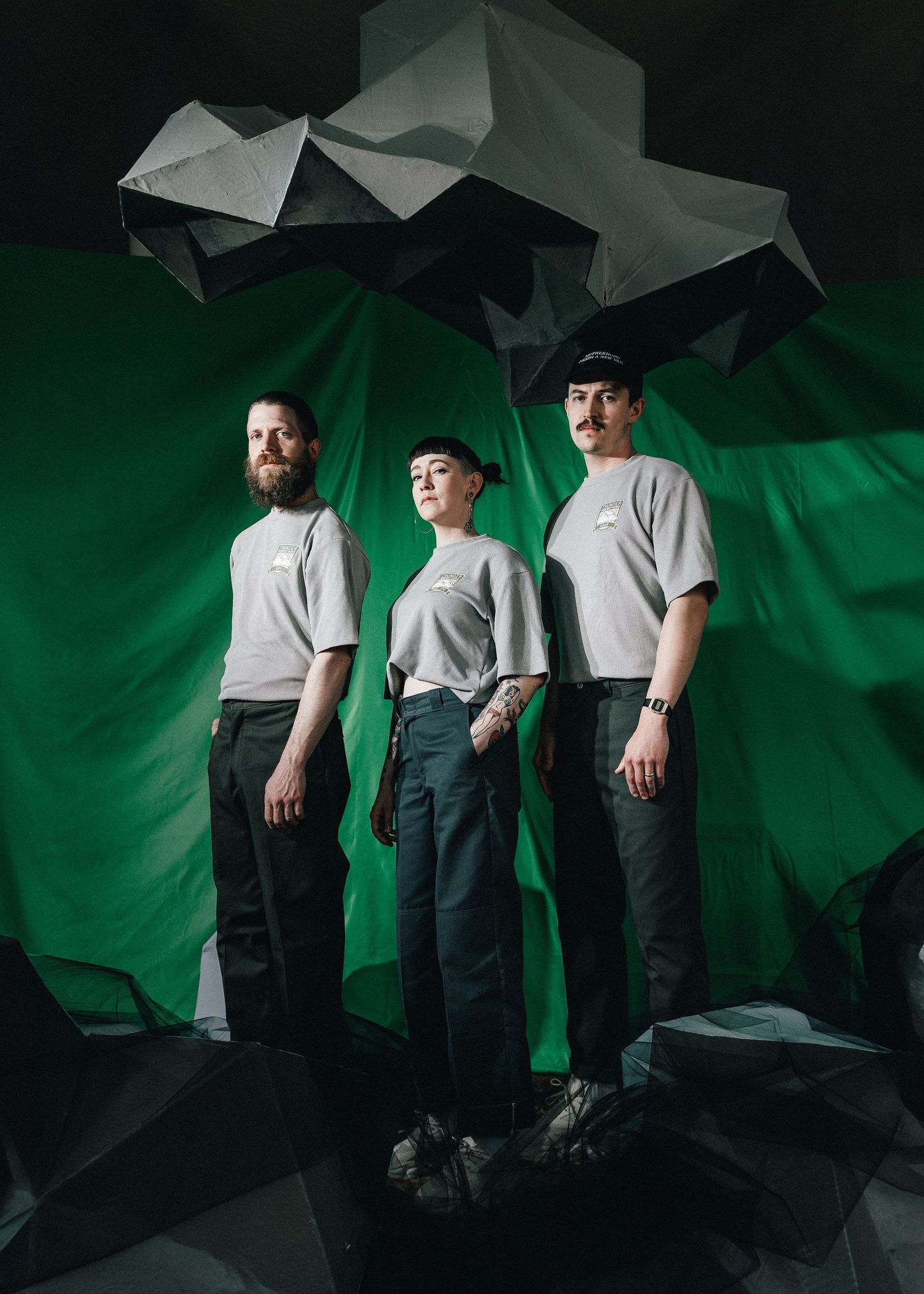 Experimental fashion portrait series showing figures in white shirts and dark pants against a dramatic green backdrop.