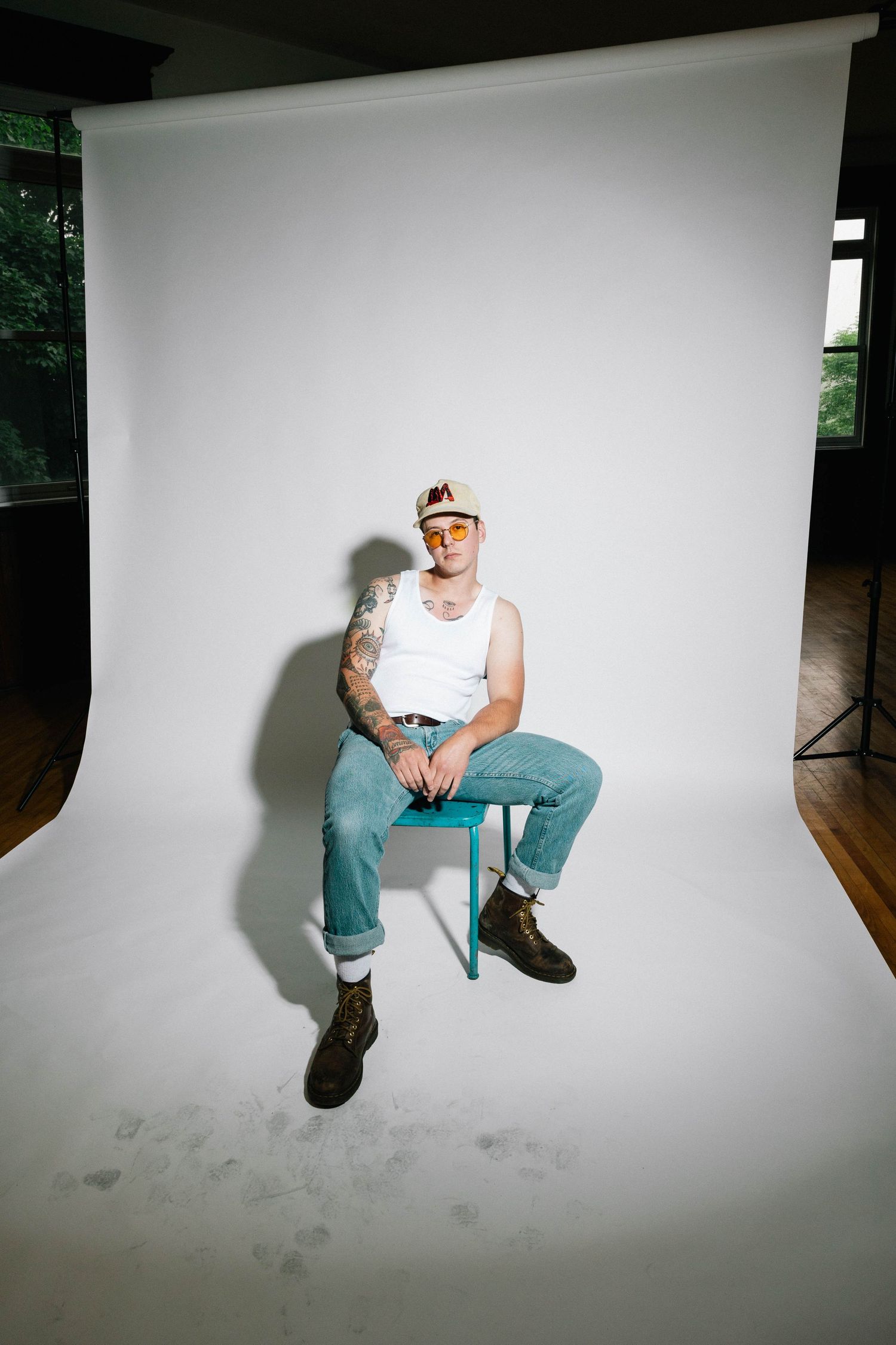 Studio photographs showing a person sitting on stark white background in casual attire from multiple angles.
