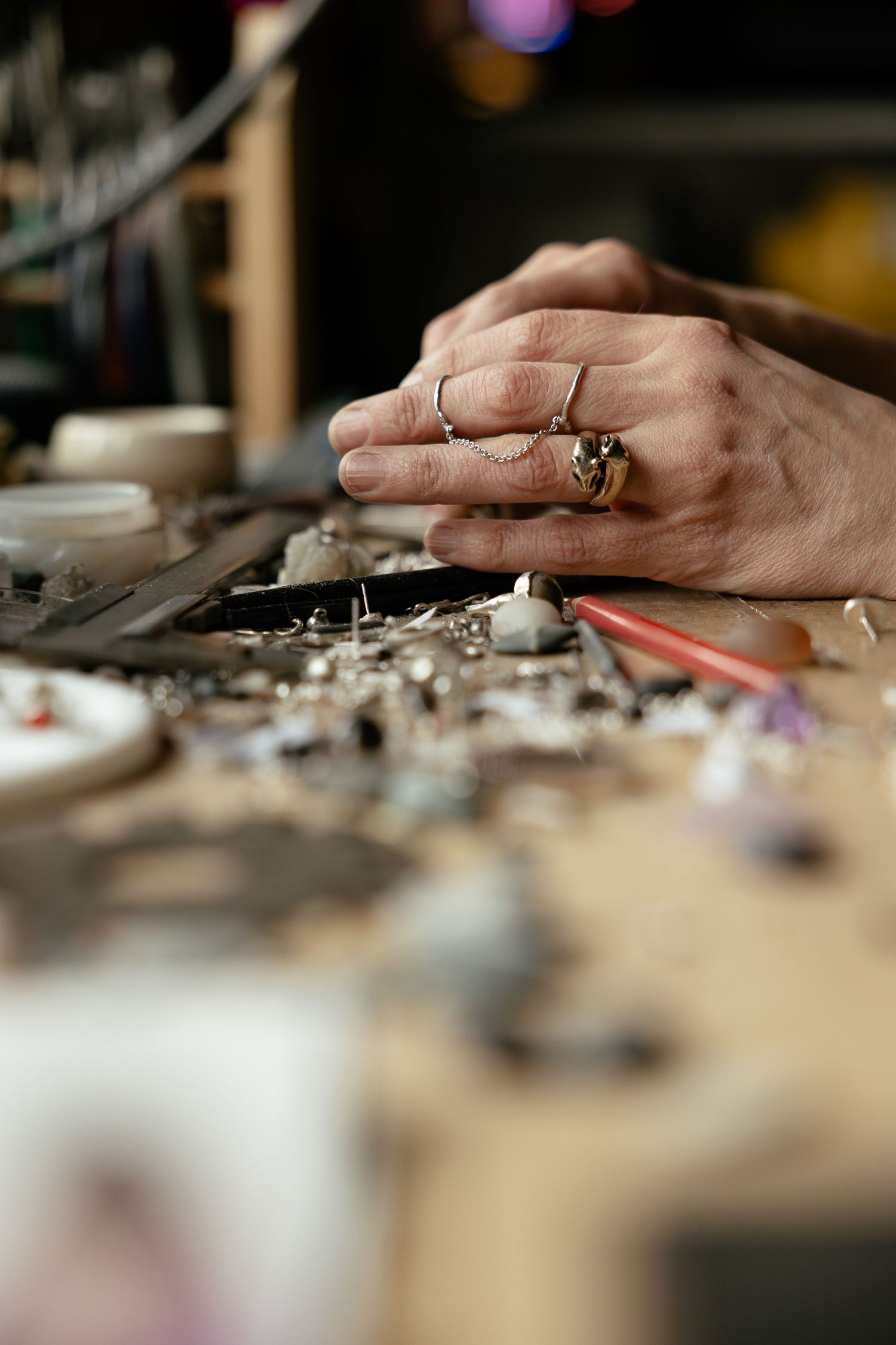 A close-up view of hands working on an electronics repair bench with scattered components and tools.