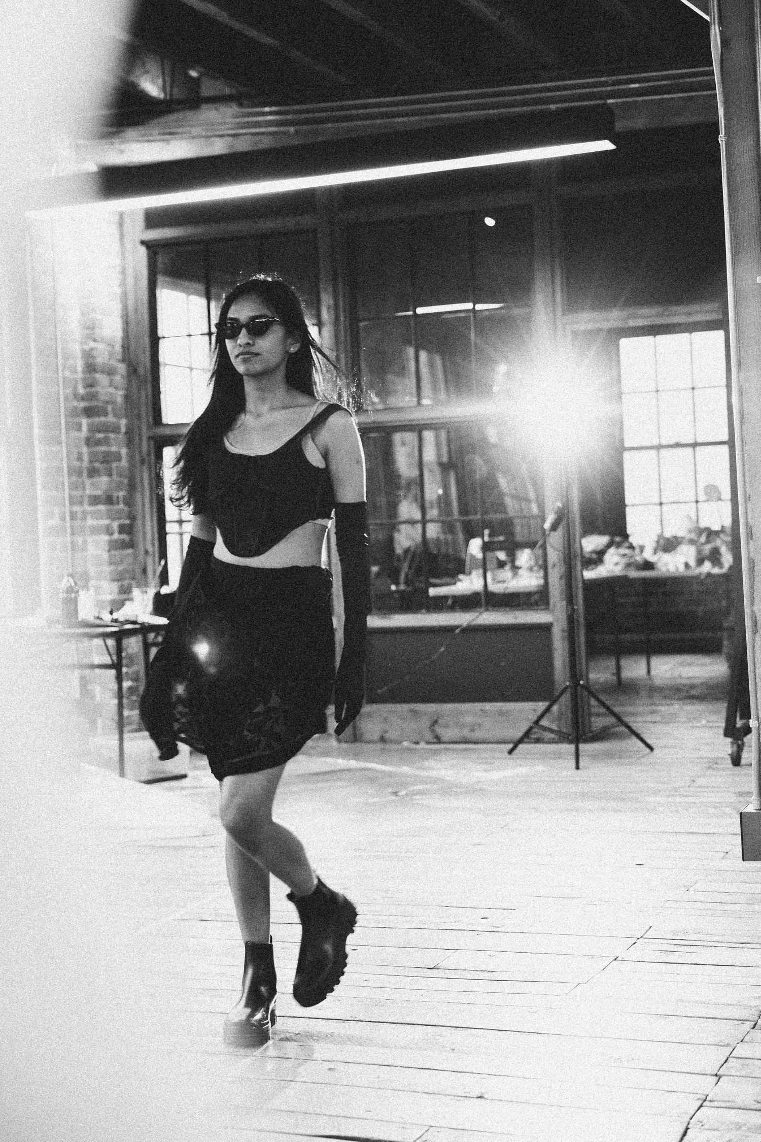 A figure in black workout attire performs dynamic dance moves in an urban studio space with dramatic lighting.