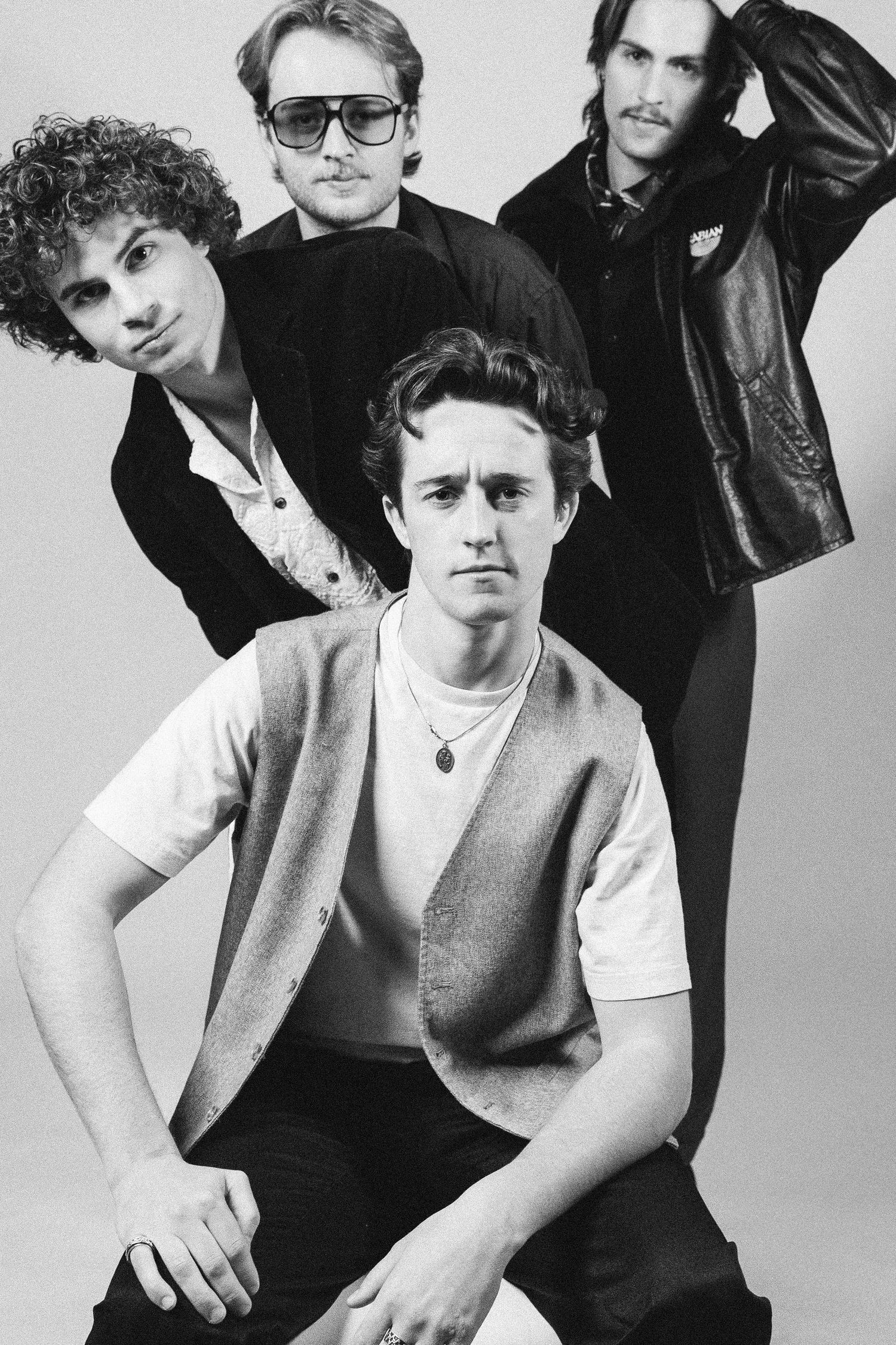 Black and white studio portrait of a rock band posing together in casual attire.