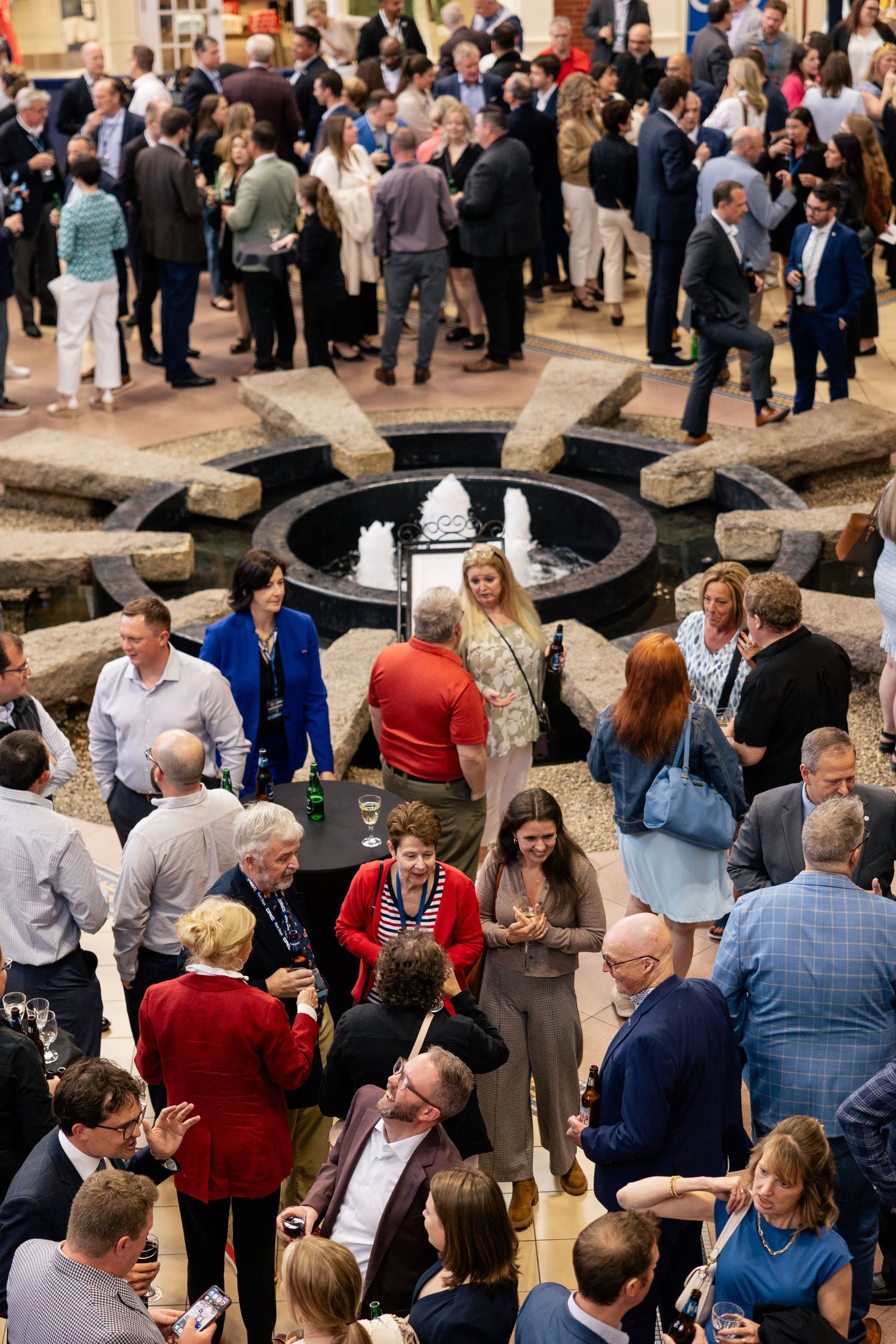 A crowded networking event shows business professionals mingling and conversing in a large indoor venue.