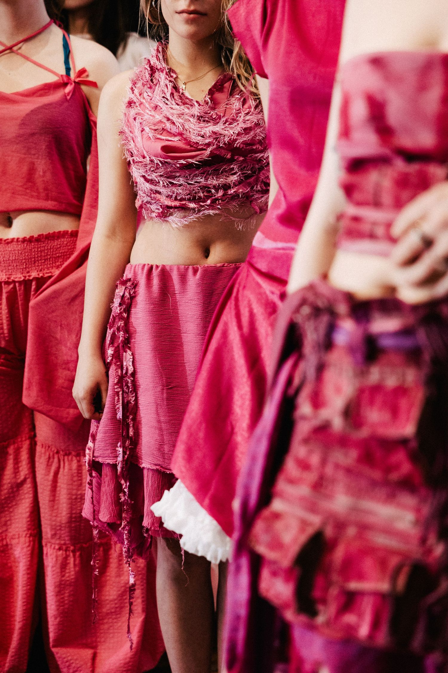 Pink fabric fashion garments with ruffled textures and crop top designs in vibrant magenta shades.