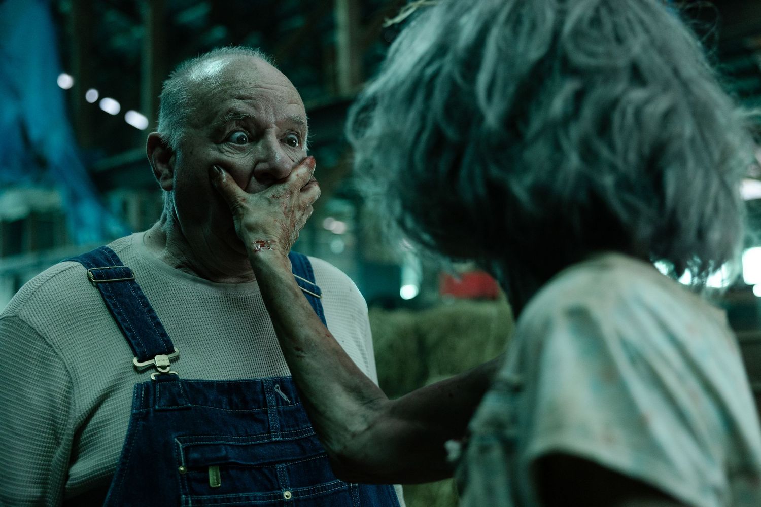 Two people in a dark scene share an intense moment with one person touching the other's face in a teal-tinted atmosphere.