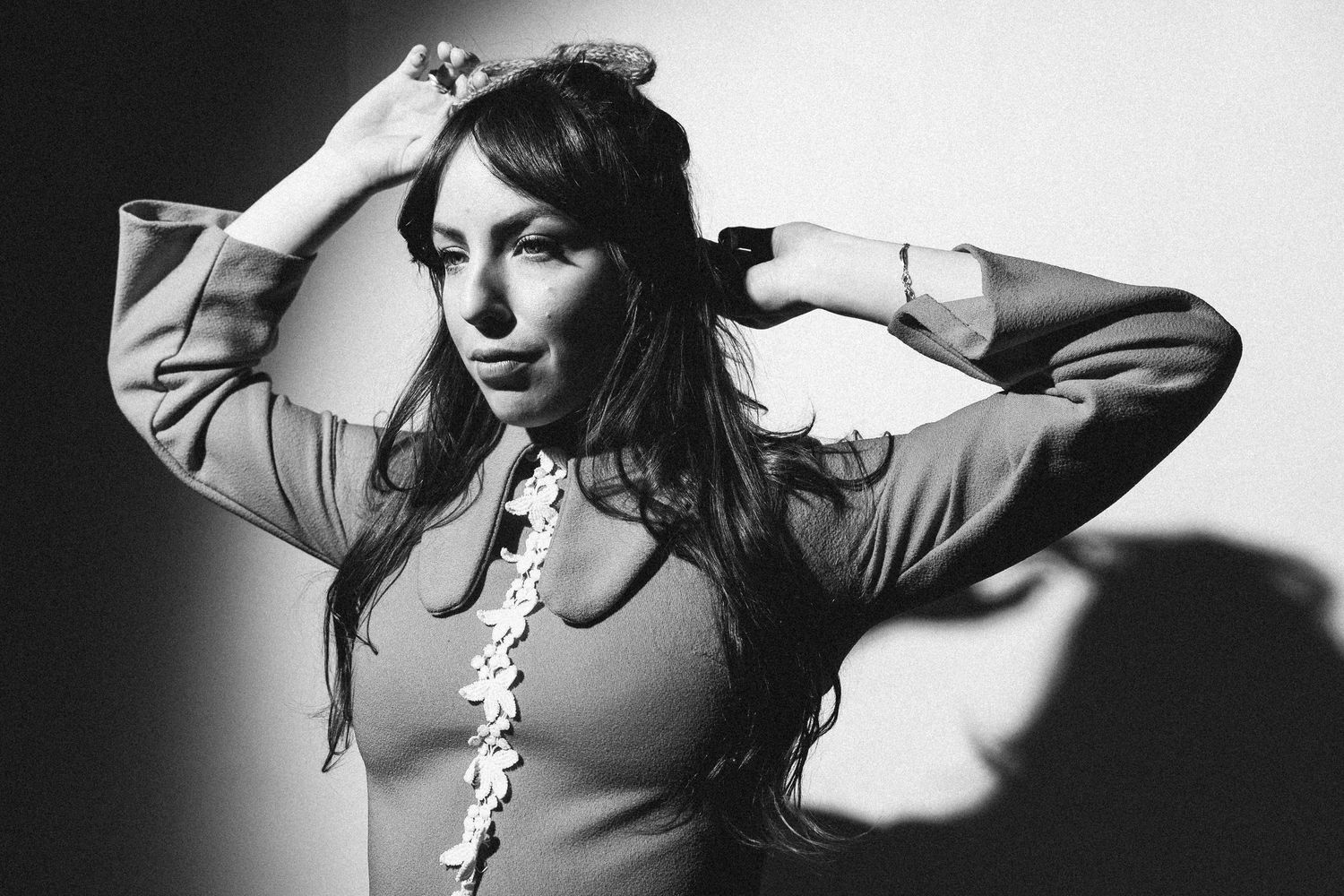 Artistic black and white portrait series showing moody dramatic poses with hair movement against dark background.