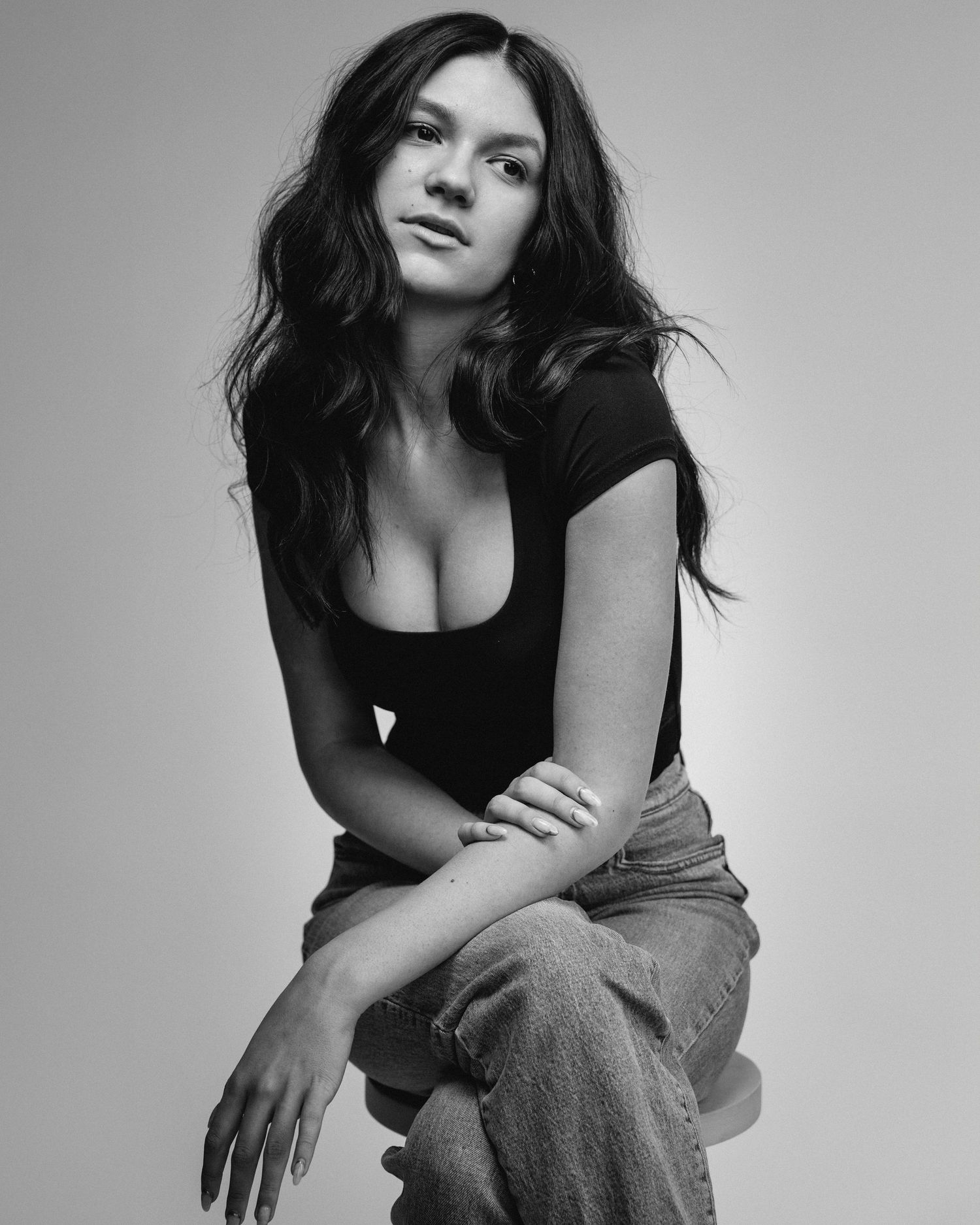 Black and white portrait of a person in casual attire with dark long hair against a light background.