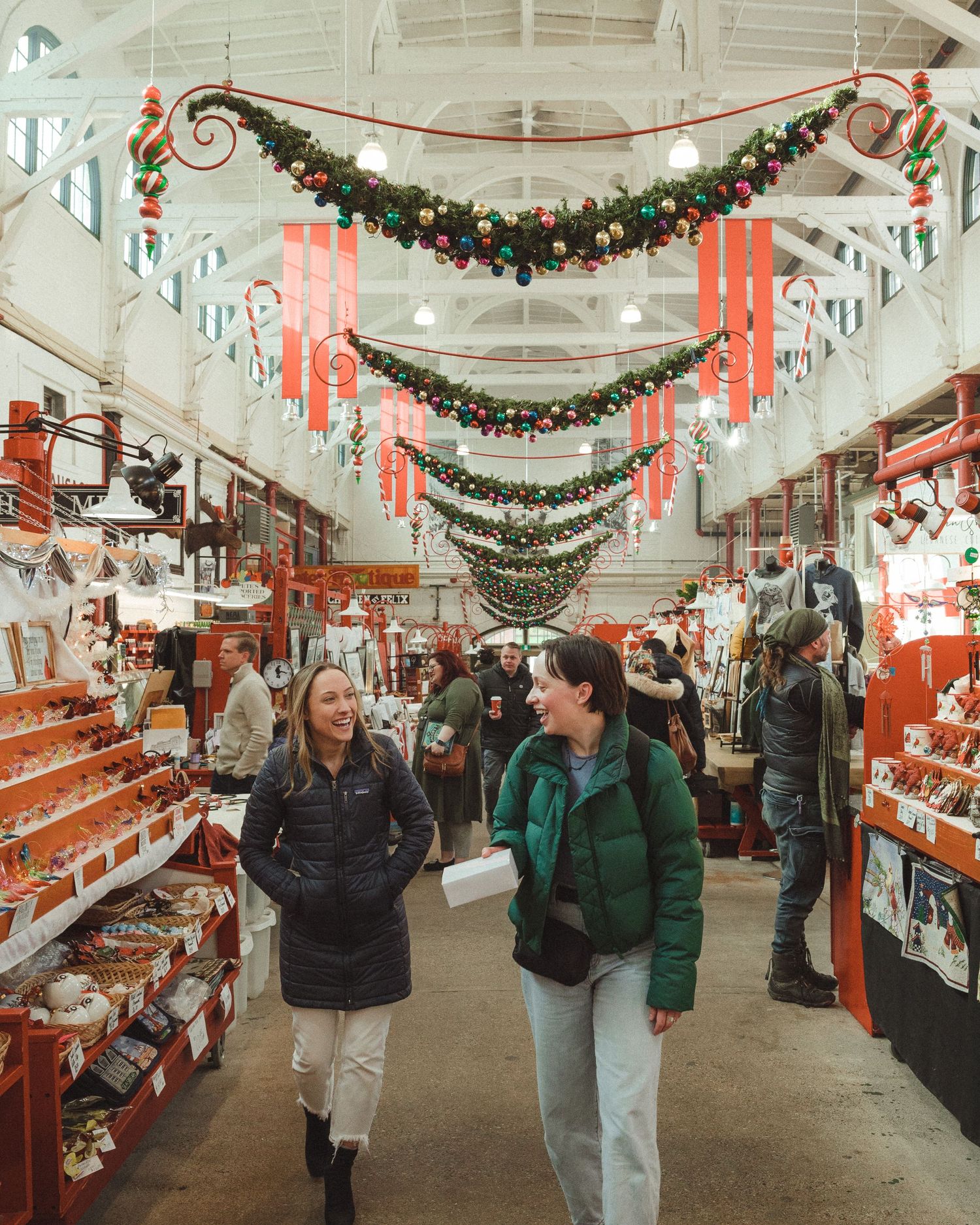 A group of shoppers browse a retail store decorated with festive Christmas garlands and ornaments during the holiday season.
