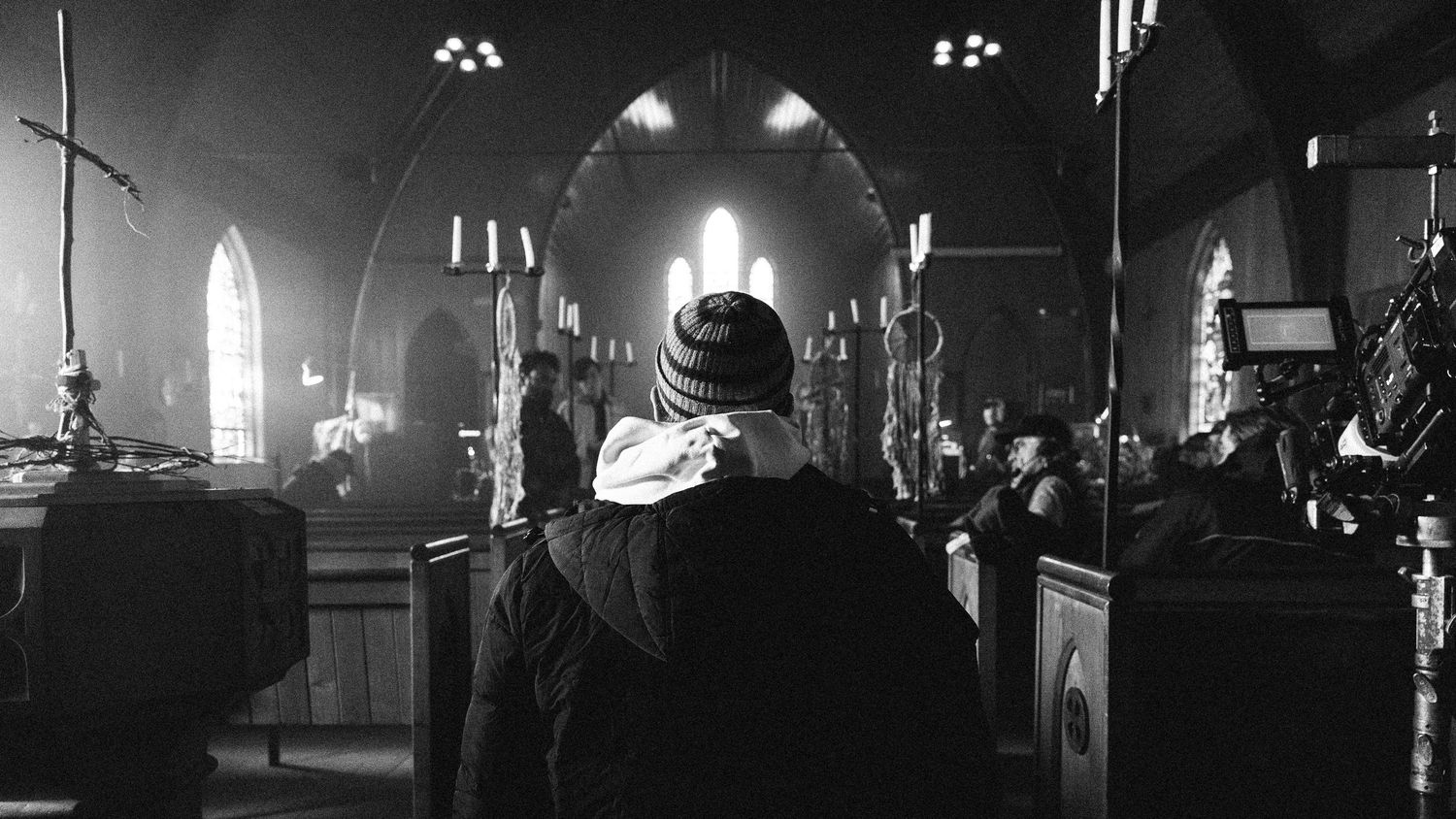 A black and white panoramic photograph shows the interior of an ornate old church with stained glass windows and arches.