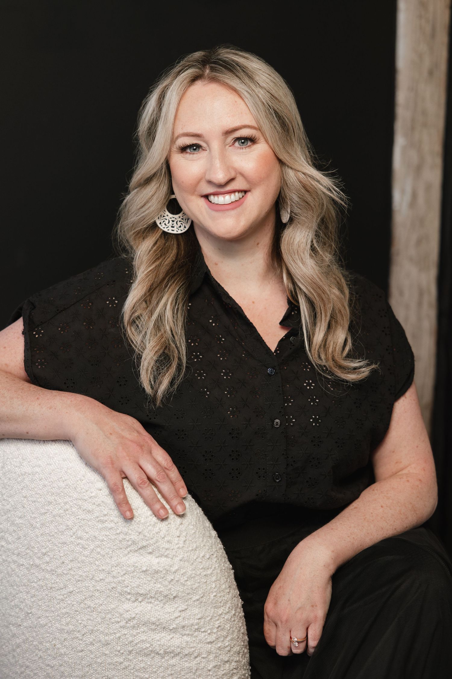 Professional portrait series showing someone in a black top posing against a black backdrop with white decorative elements.
