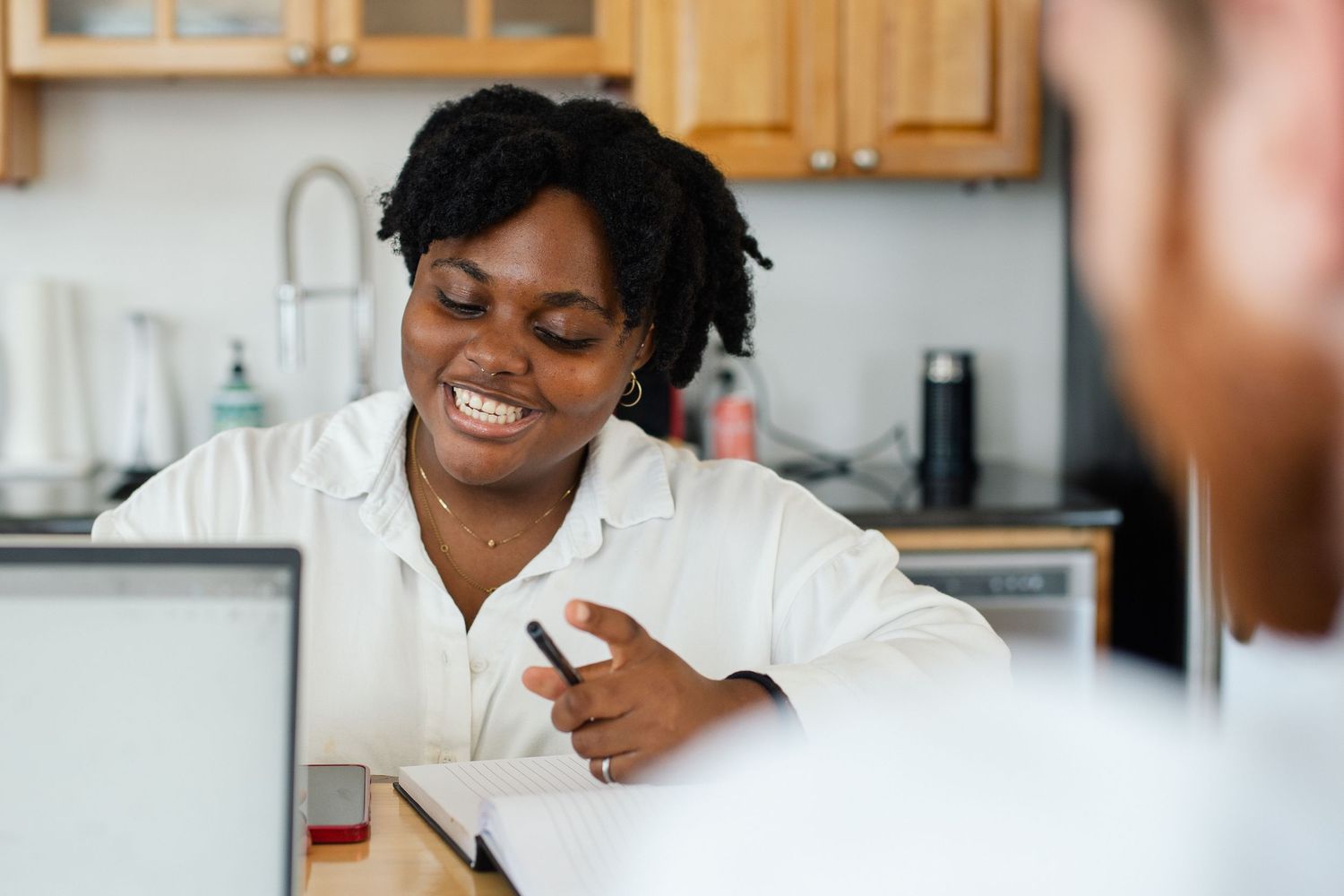 Professional meeting taking place in a bright kitchen setting with laptop visible on counter.