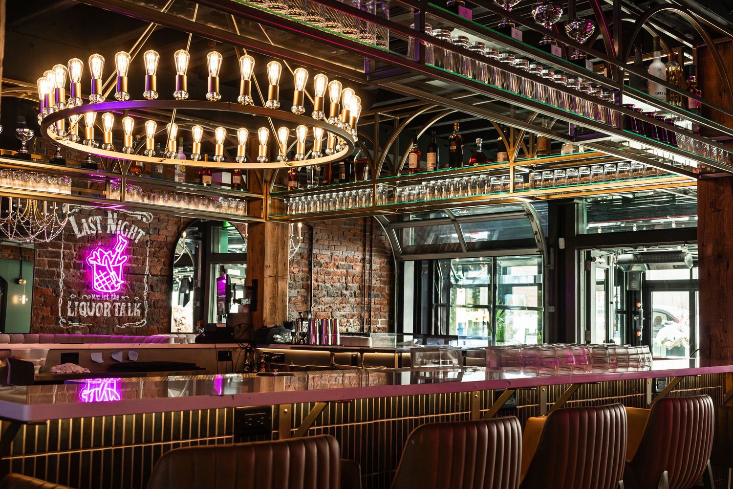 Elegant bar interior with circular chandelier and leather seating features rich wood accents and ambient lighting.