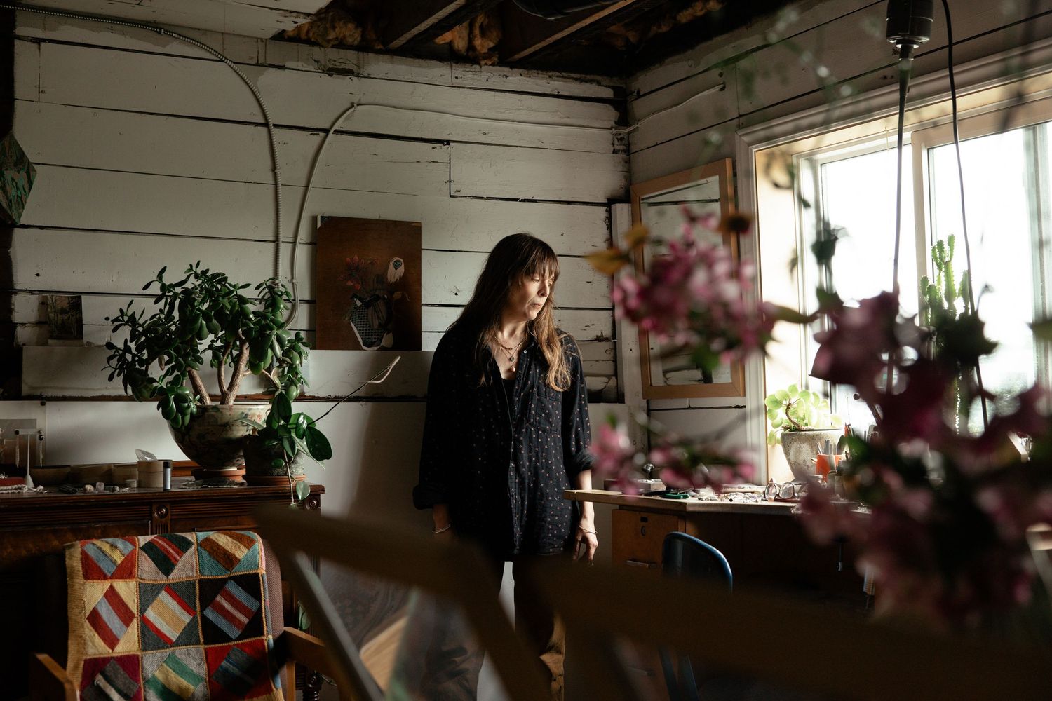 A cozy bohemian sunroom decorated with hanging plants and colorful textiles catches golden afternoon light.