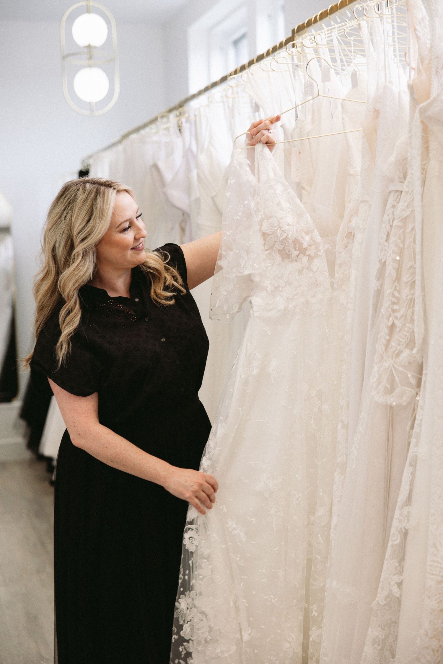 Bridal boutique interior showing rows of white wedding dresses with natural lighting.
