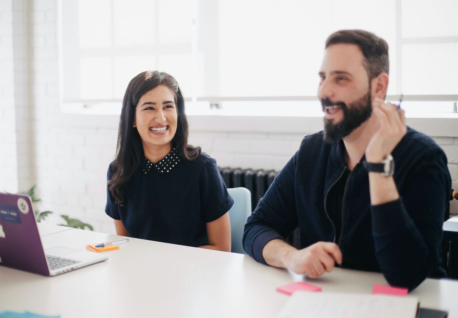 Business colleagues in casual attire collaborating at a modern office table during a meeting.