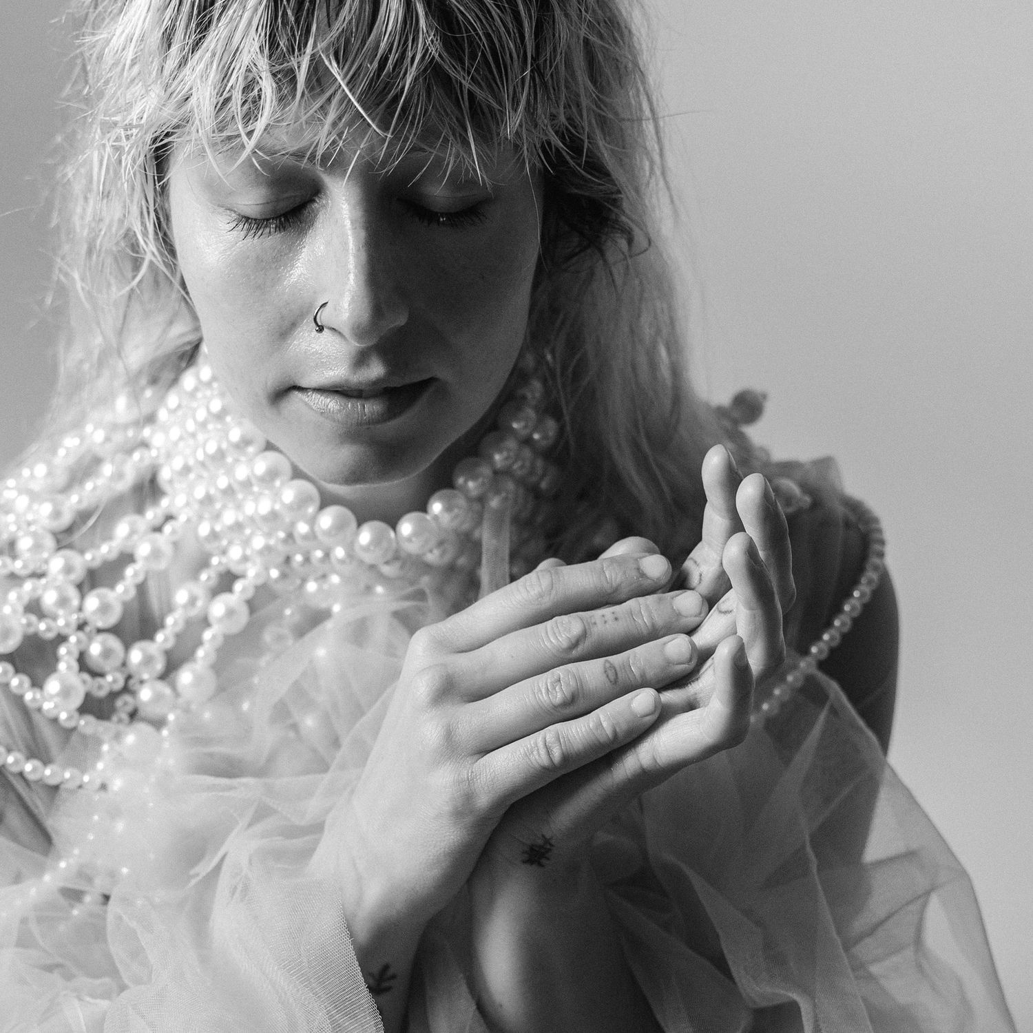 Black and white artistic portrait series showing a person holding and blowing baby's breath flowers with dreamy expression.
