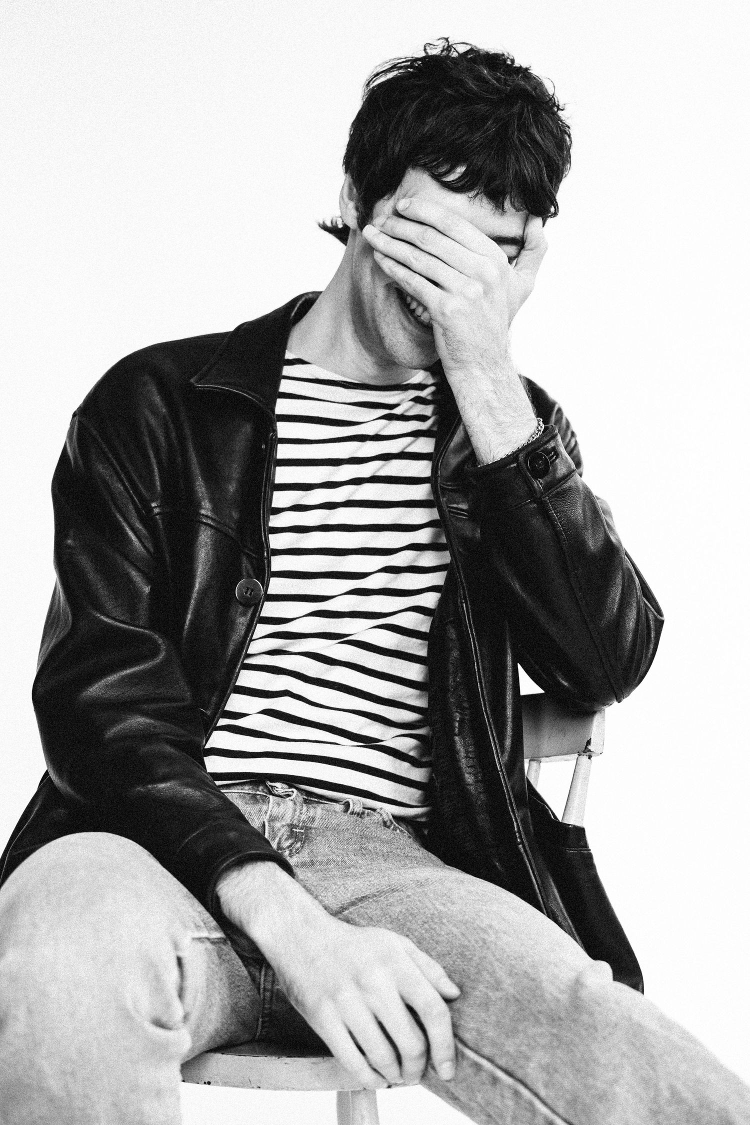 Person with striped shirt and black jacket shown in four similar poses hiding their face with their hand.