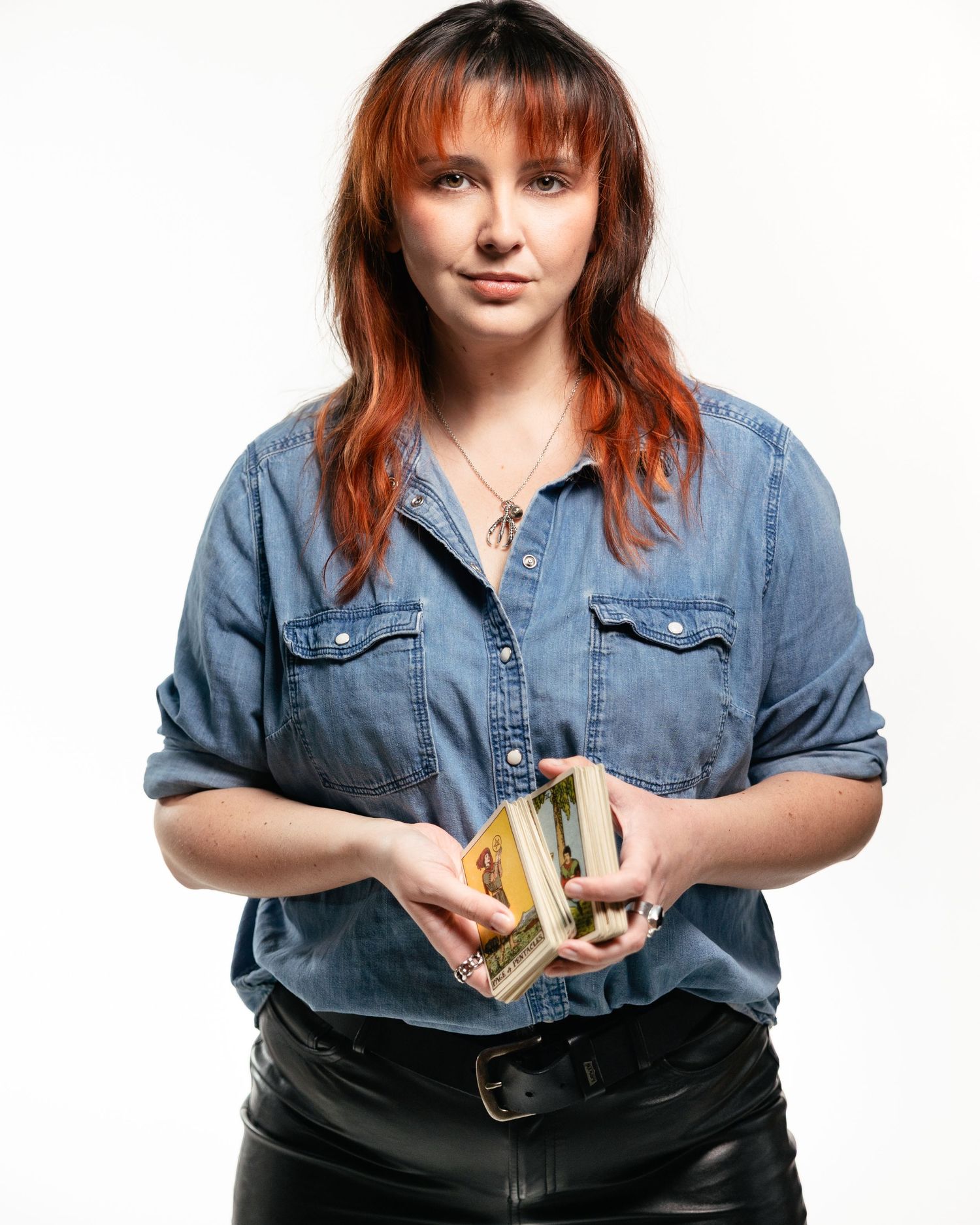 Person in casual denim shirt holding a stack of money against white background.