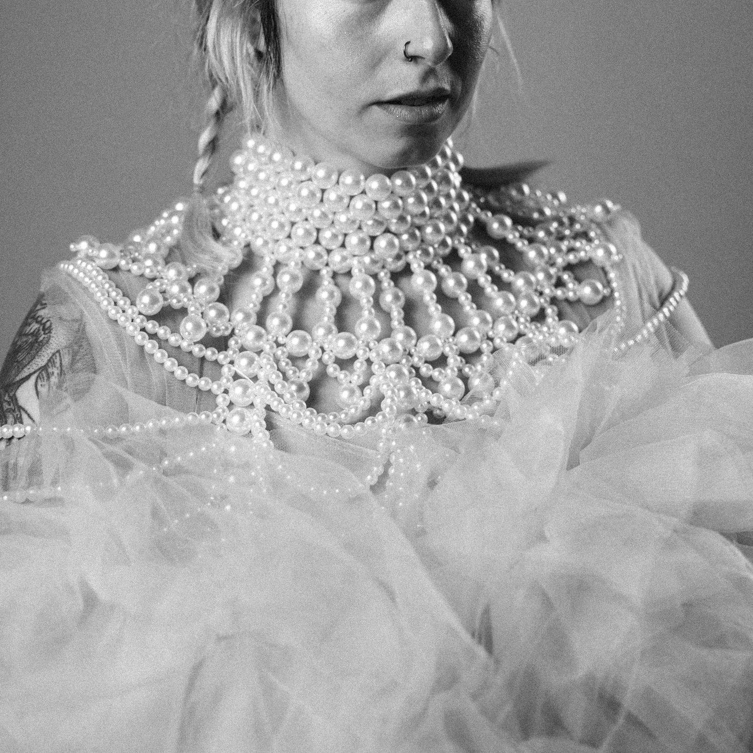 Black and white close-up portraits showing ornate pearl collar neckpieces with dramatic tulle fabric styling.