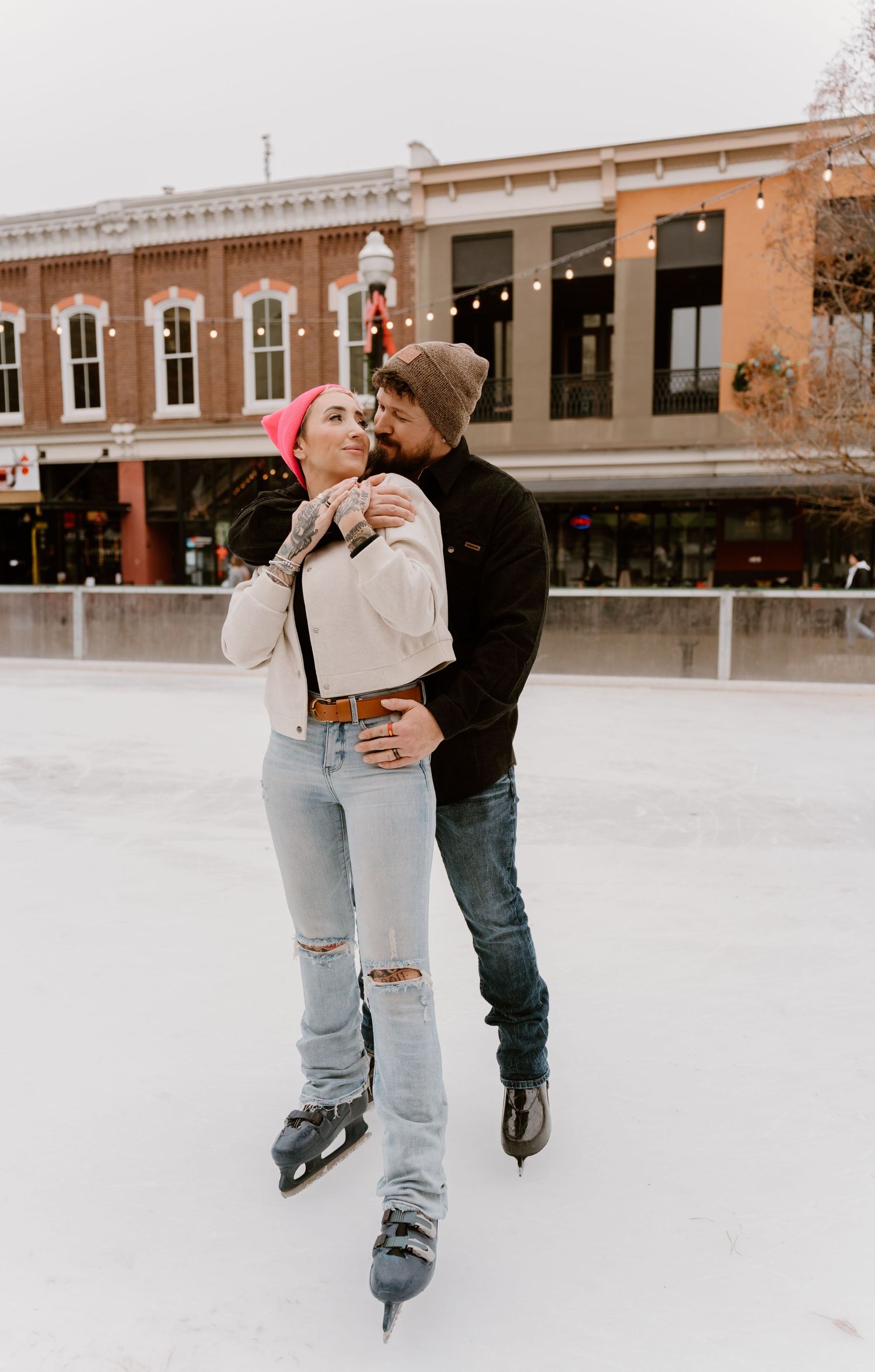 Ice skating couple shares romantic moment on outdoor rink in winter.