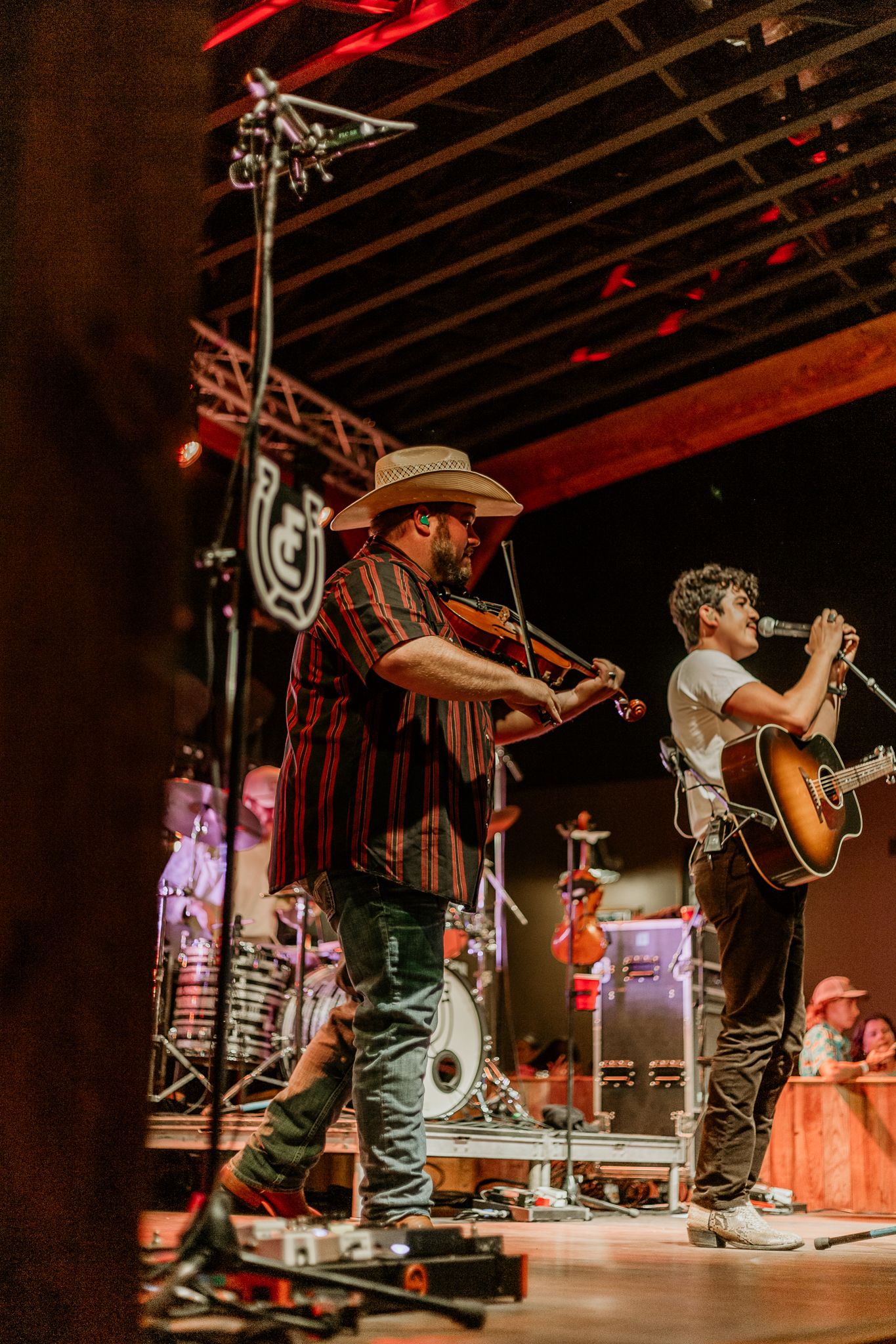 Musicians lined up on stage with guitars and cowboy hats during energetic performance.