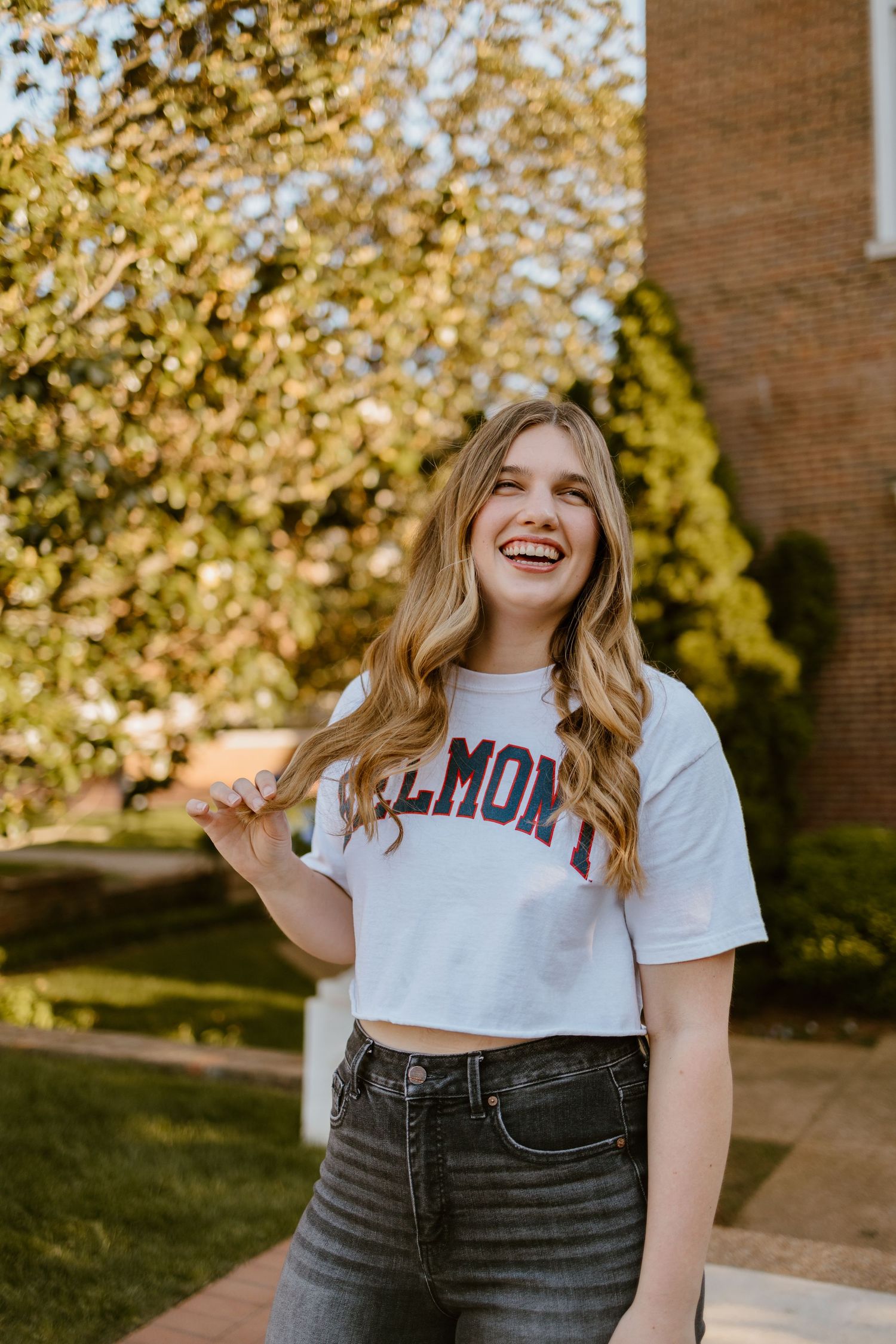 Casual outdoor portrait wearing Belmont university crop top with autumn trees in background.