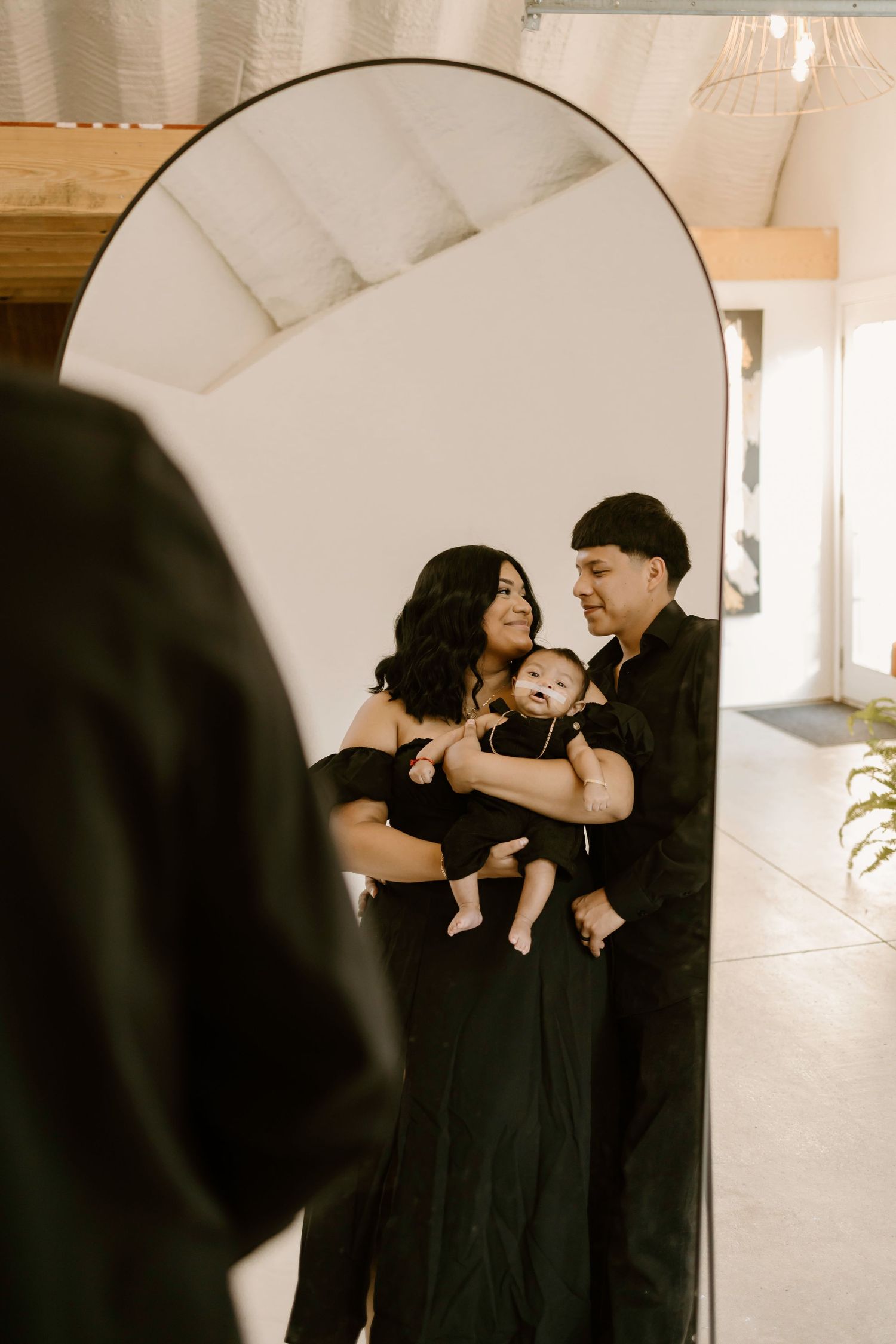 Couple in black attire sharing intimate moments against white interior with mirror.