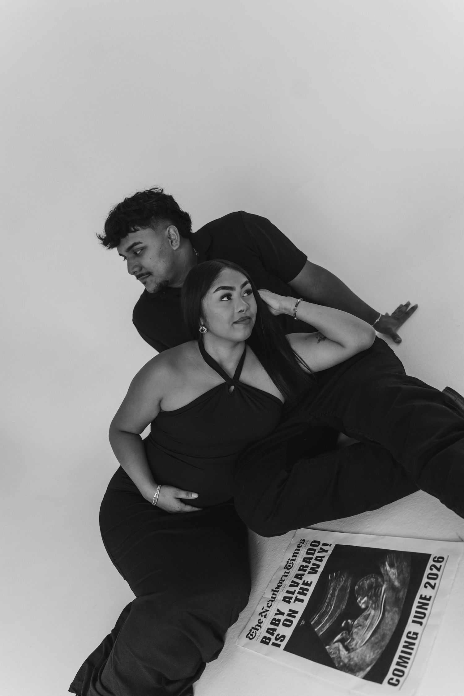 A series of black and white photos showing someone in dark clothing reclining and posing with a newspaper.