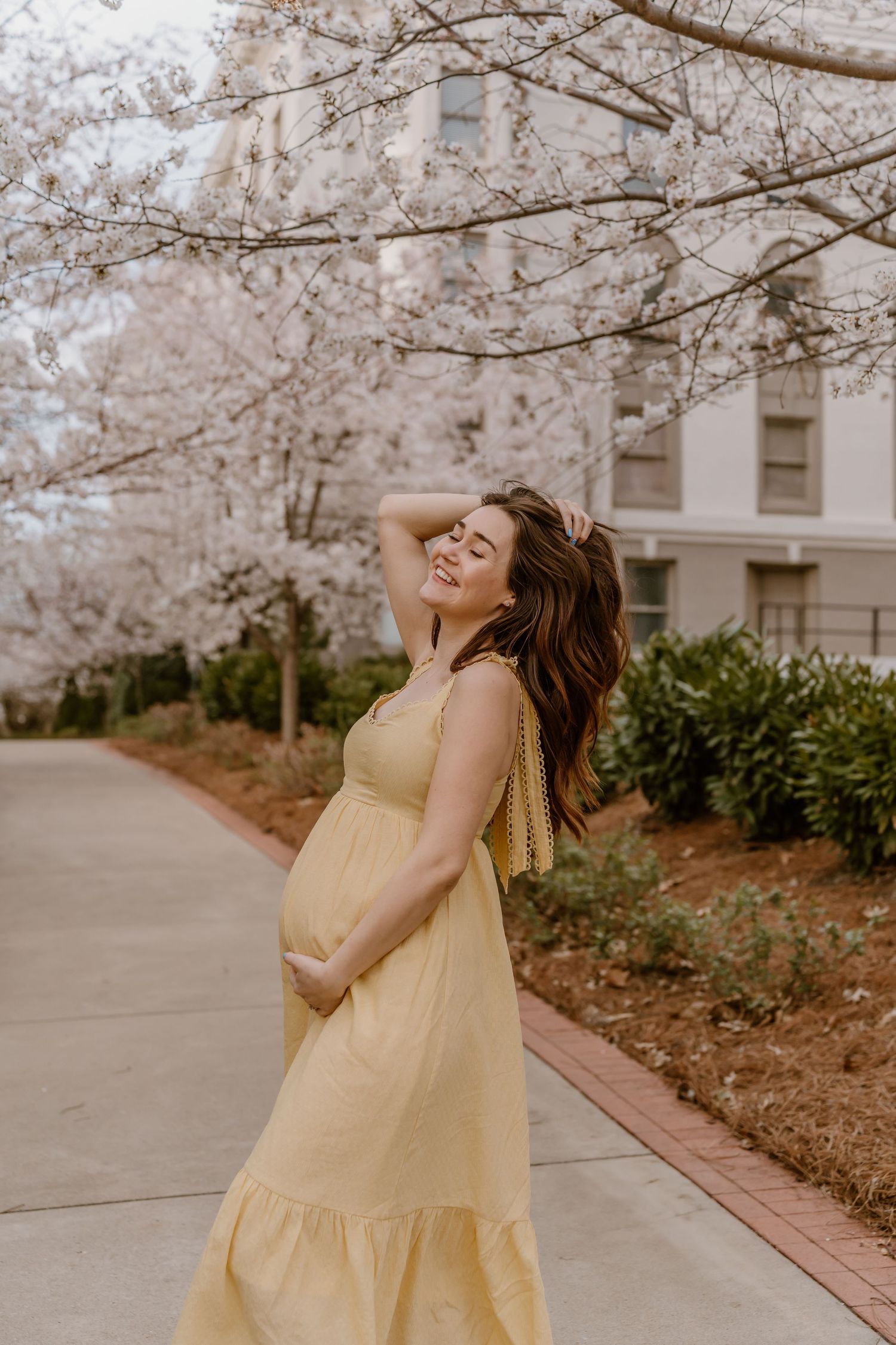 Soon to be mom twirling under blooming cherry blossom trees in springtime in Nashville, Tennessee.