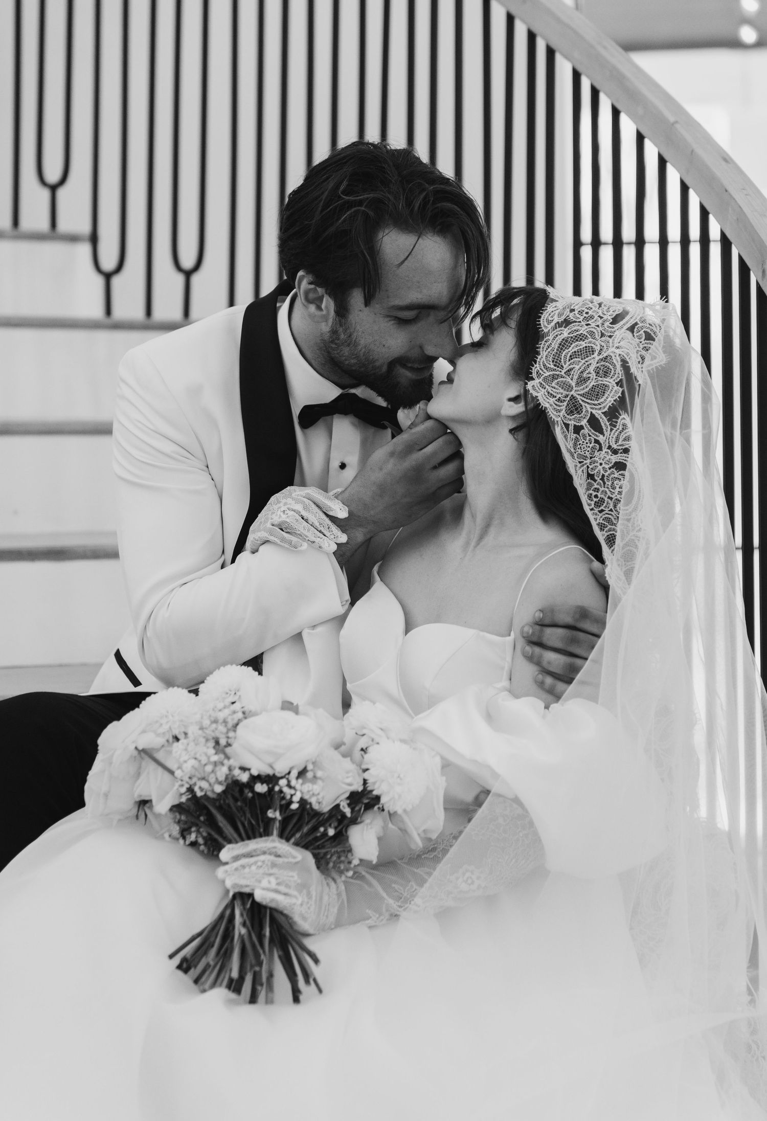 Black and white wedding photography in an elegant indoor setting with geometric railings.