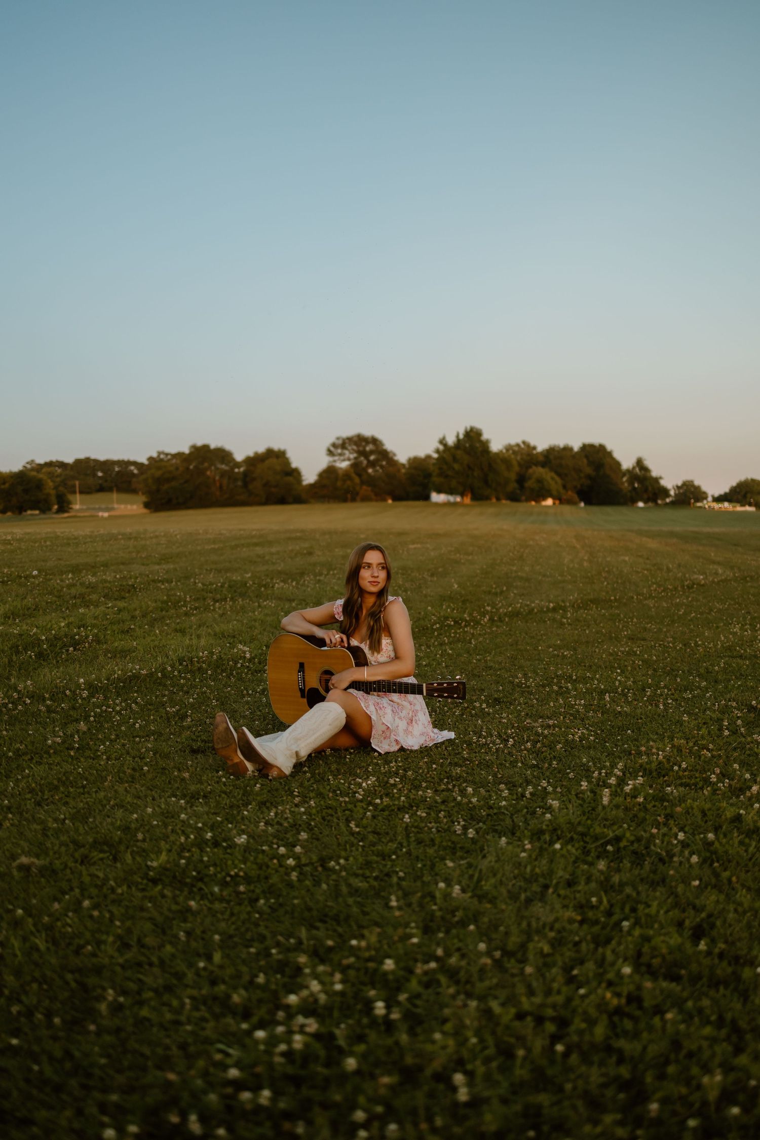 A sunset portrait session in a wildflower meadow with acoustic guitar and flowing dress.