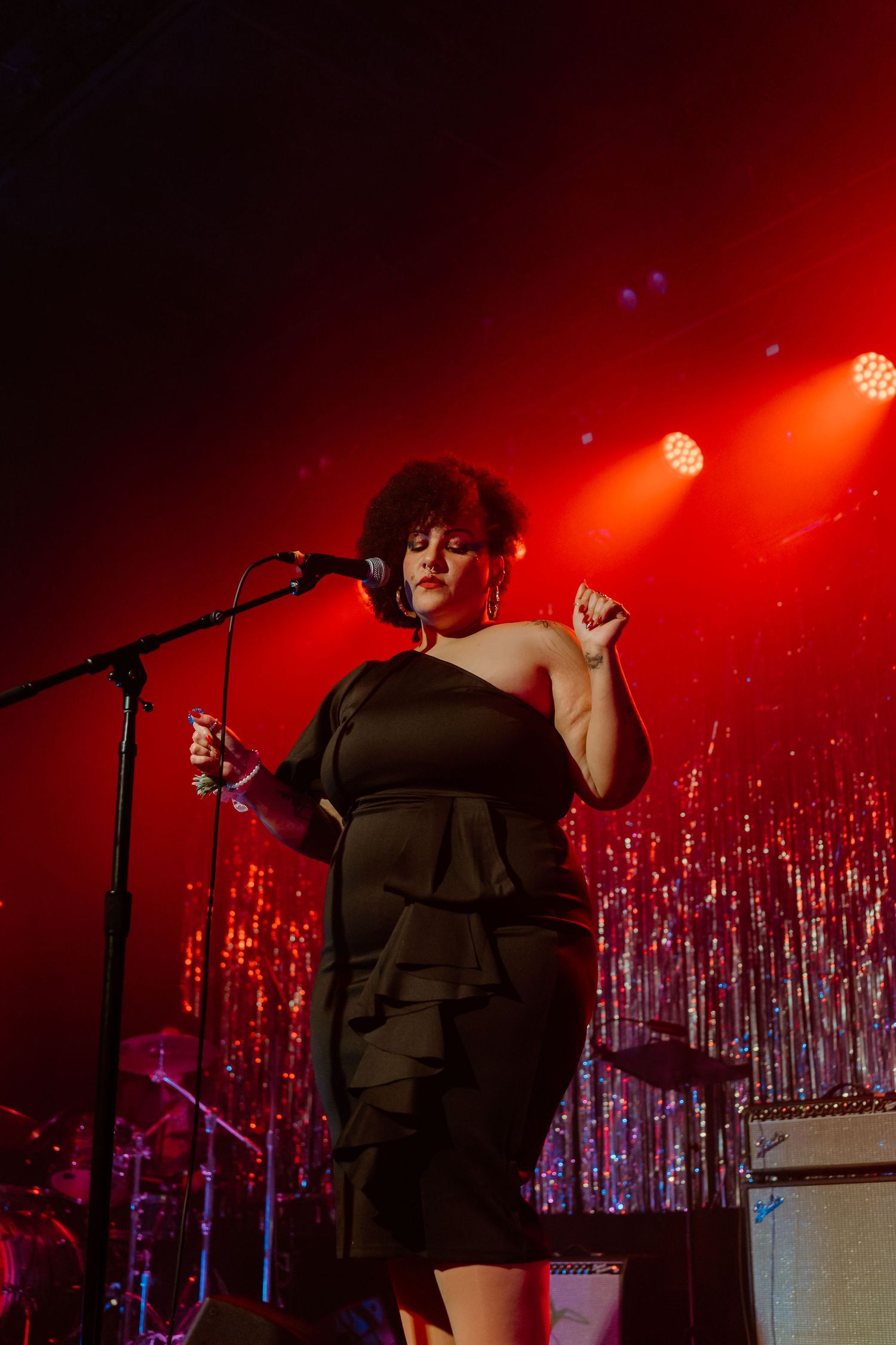 Performer on stage with red lighting and silver tinsel backdrop during an energetic show.