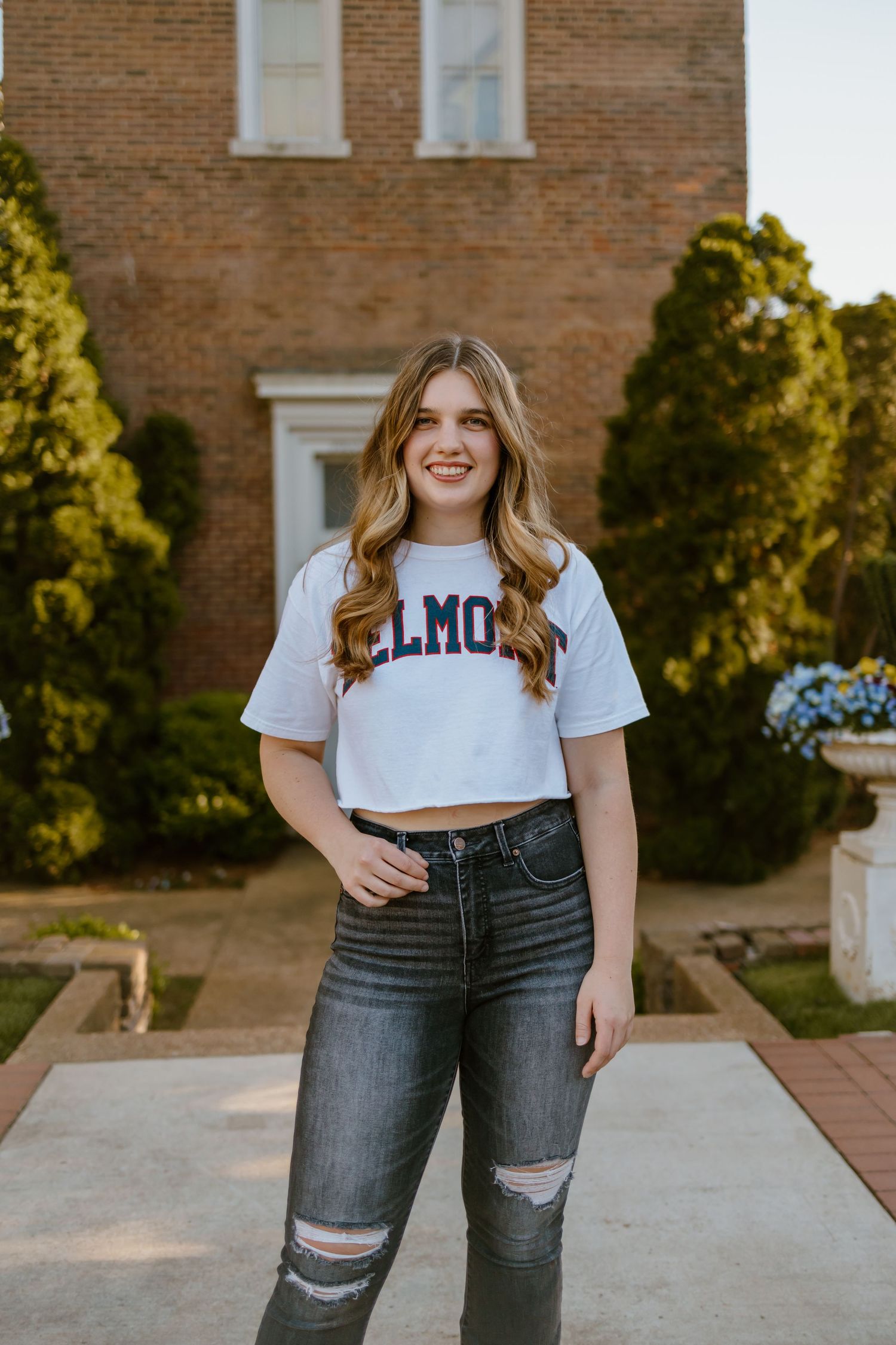 A cropped white t-shirt paired with distressed dark denim jeans in an outdoor casual fashion setting.